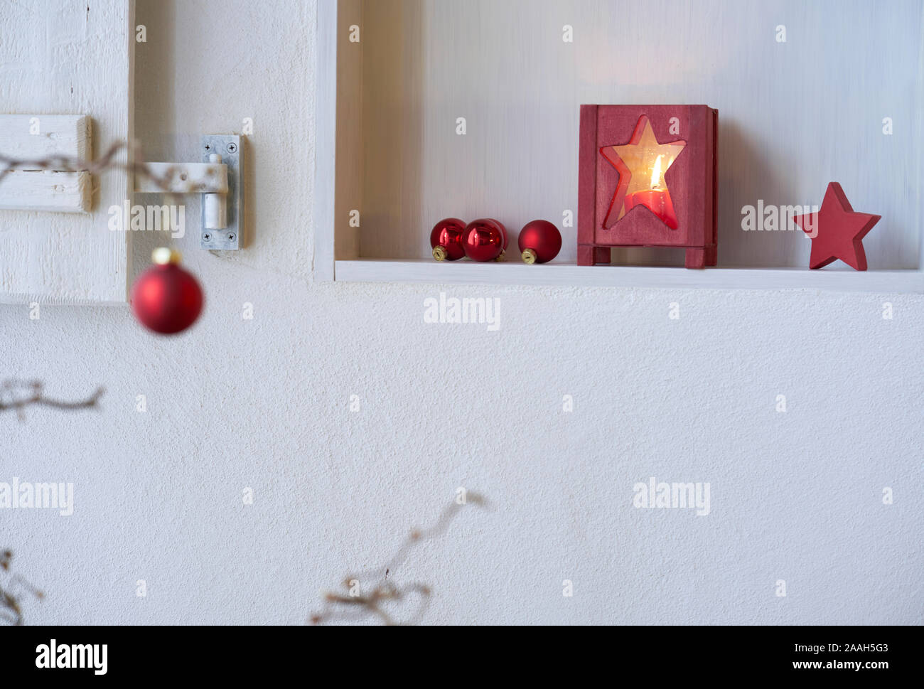Unsharp red palla di Natale presso una filiale nella parte anteriore di un ripiano con red decorazione di Natale, lanterna con la luce di una candela, spazio di copia Foto Stock