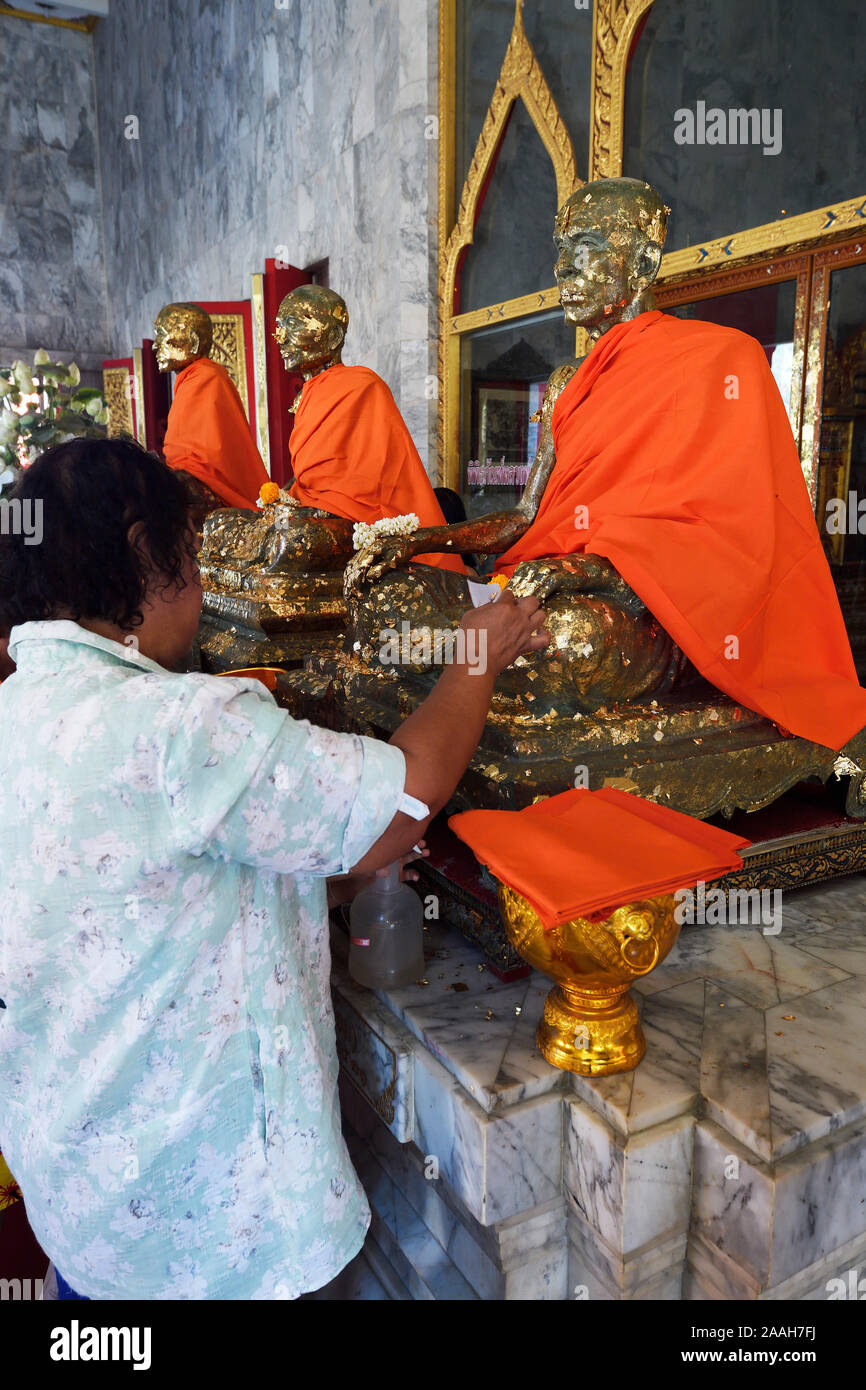 Gläubige bekleben Statuen von Mönchen mit Blattgold, Wat Chalong, größter Tempel auf Phuket, Tailandia Foto Stock
