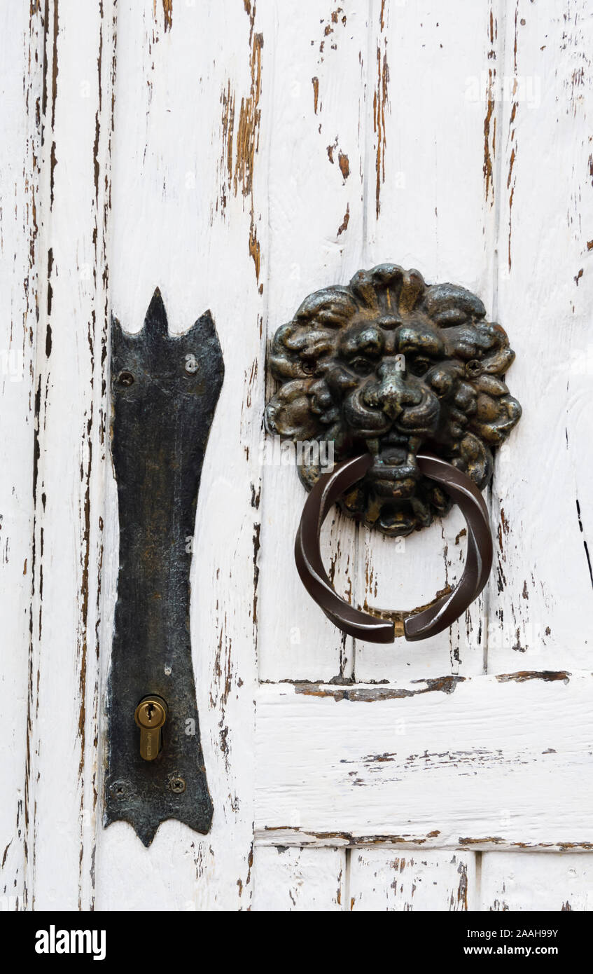 Antique maniglia della porta nella forma di un leone in un bianco porta di legno, close-up Foto Stock