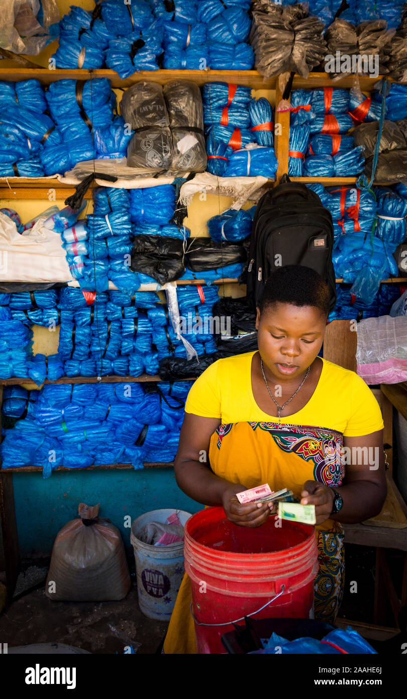 Le donne a contare i soldi in un salto nel mercato Mzuzu, Malawi, vendita di blu e nero di sacchetti di plastica Foto Stock