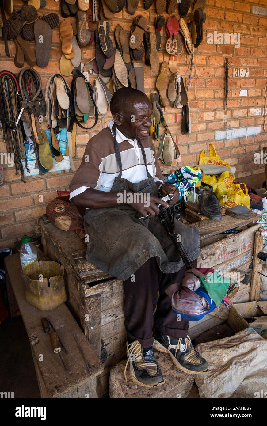Un stallholder nel mercato Mzuzu, Malawi, riparazioni di calzature Foto Stock