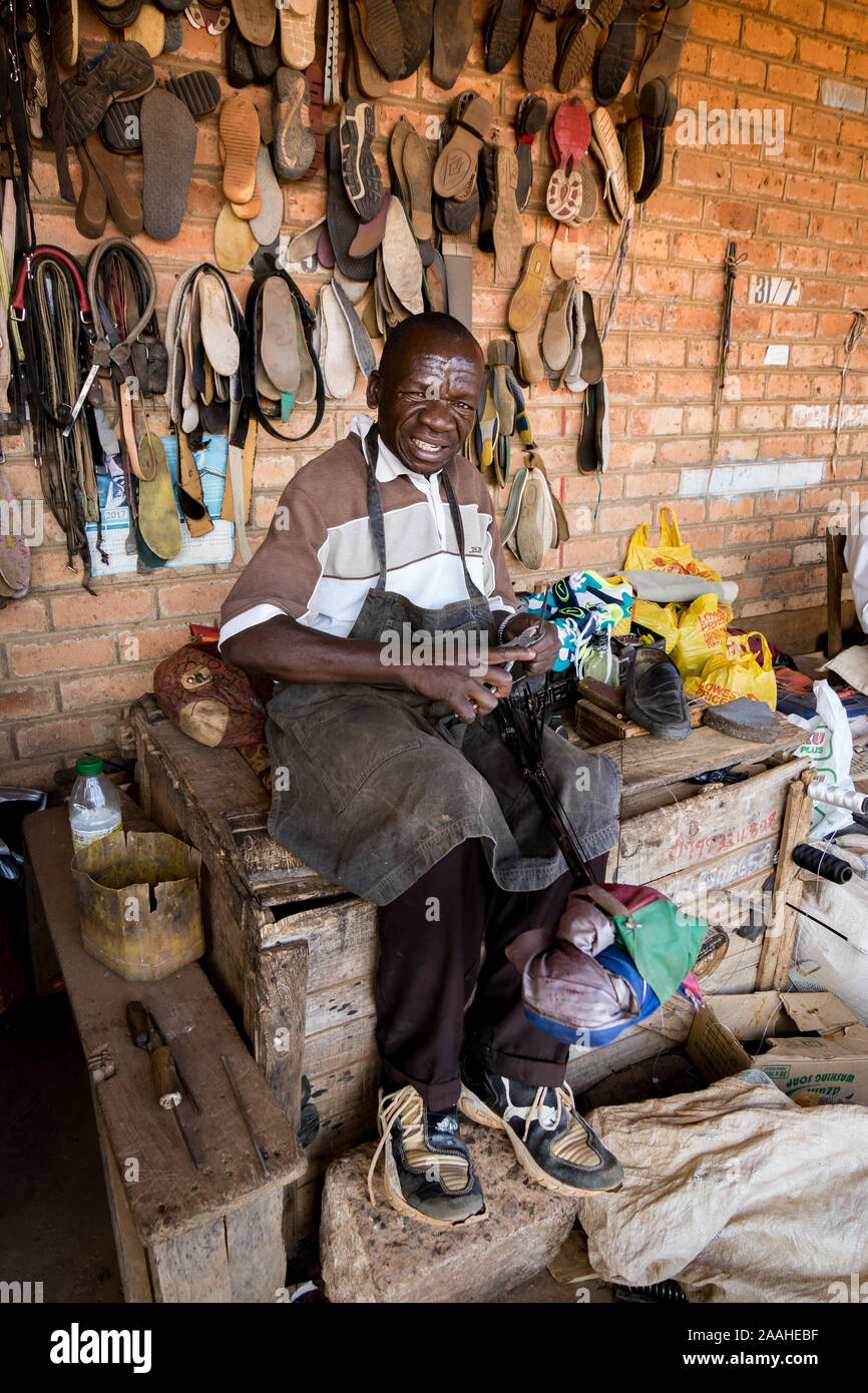 Un stallholder nel mercato Mzuzu, Malawi, riparazioni di calzature Foto Stock