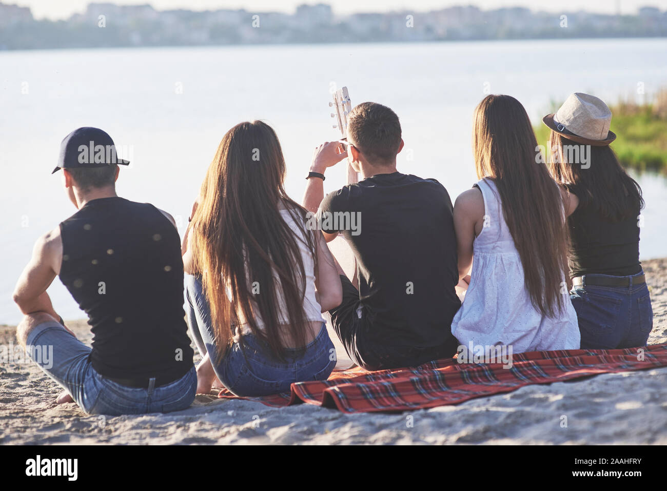 Happy amici divertirsi sulla spiaggia - i giovani seduti in aria aperta sulle vacanze estive Foto Stock