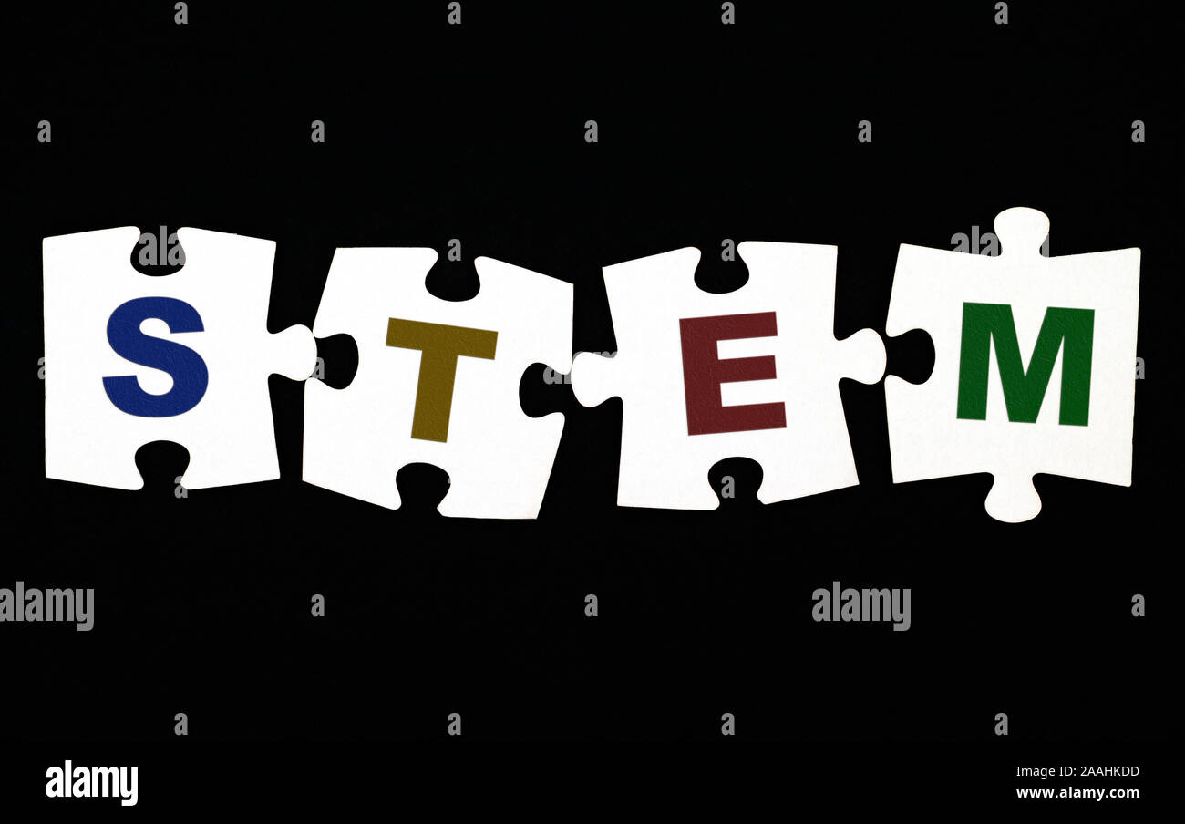 Quattro pezzi di un puzzle con lettere stelo (Scienza, Tecnologia e Ingegneria Matematica) su sfondo nero. Close-up. Foto Stock