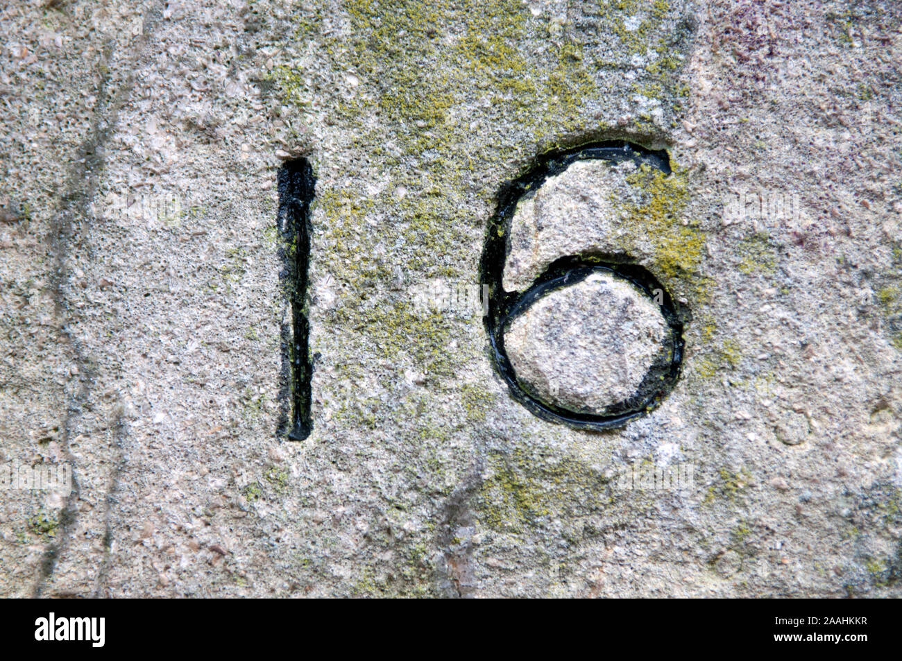 Un primo piano del numero sedici in pietra ed evidenziato in vernice nera Foto Stock