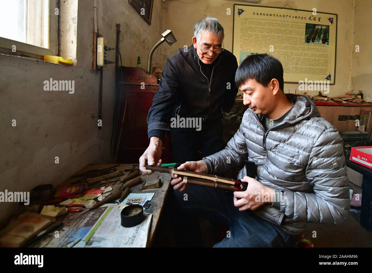 (191122) -- ZHENGZHOU, nov. 22, 2019 (Xinhua) -- Mao Zhiyuan (L) guida il suo figlio Mao Guoyong in fase di assemblaggio di Sheng in Luoyang, centrale cinese della Provincia di Henan, nov. 21, 2019. Mao Zhiyuan, 65, era nato in una famiglia con una lunga storia nel rendere Sheng, un Cinese tradizionale soffiato a bocca. zampogna strumento. Come la quinta generazione di una Sheng-rendendo la famiglia, Mao ha iniziato a imparare il mestiere all'età 16. Dopo anni di hardwork, Mao migliorato il craft, dando l'antico strumento più ampie gamme di vocal e mutevoli piazzole. Mao artigianato è riconosciuta come una provinciale culturale immateriale heritag Foto Stock