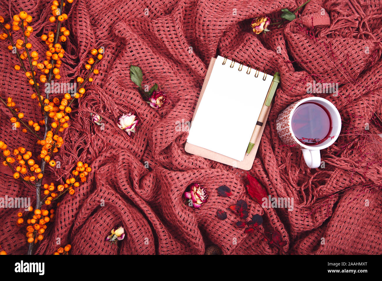 Composizione d'autunno. Tazza di tae, coperta, notebook con penna, rosa appassita. Appartamento laico, vista dall'alto, spazio di copia Foto Stock