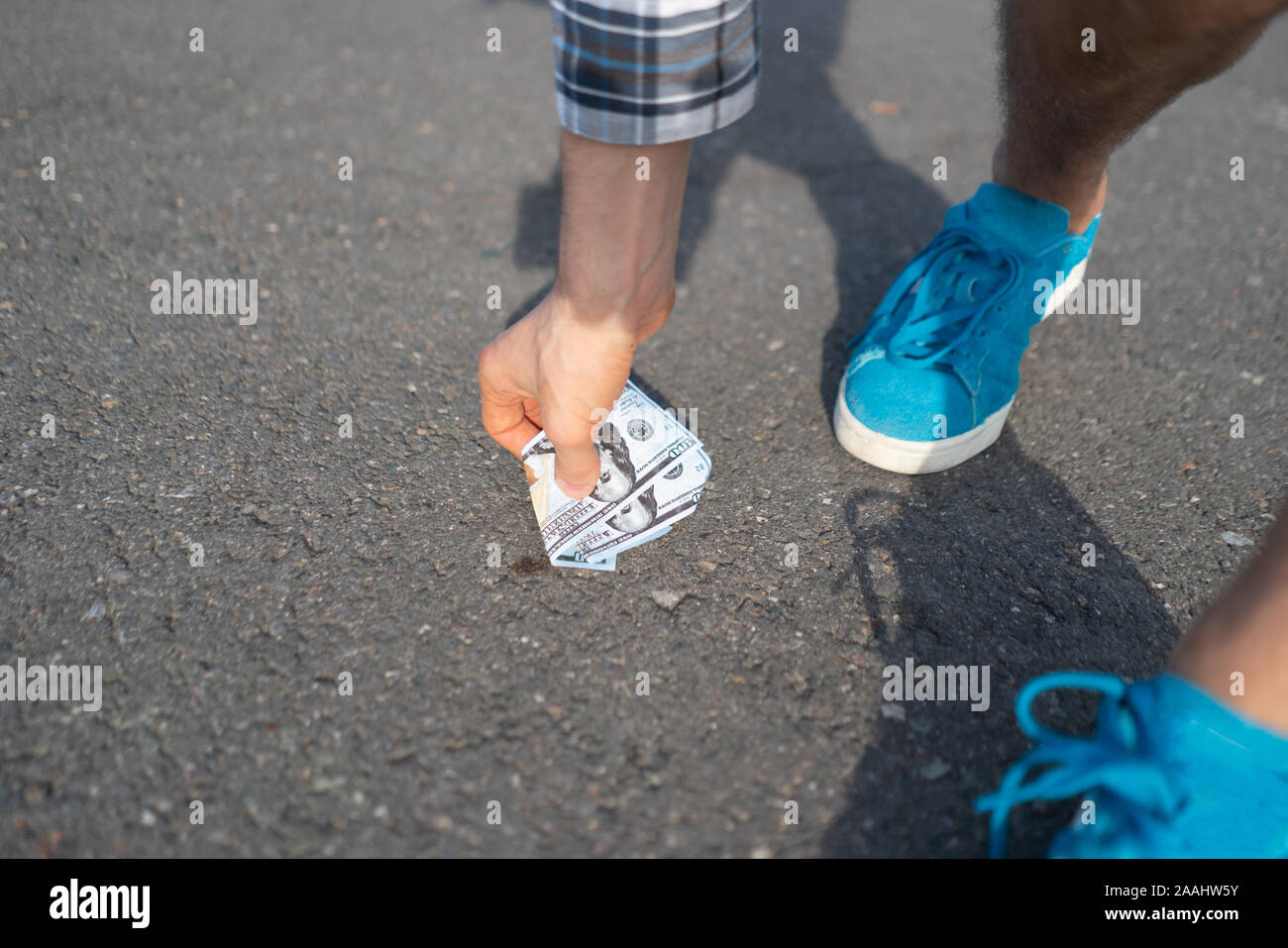 Persona trova la carta moneta perduta e lasciato cadere sul terreno asfaltato all'aperto Foto Stock