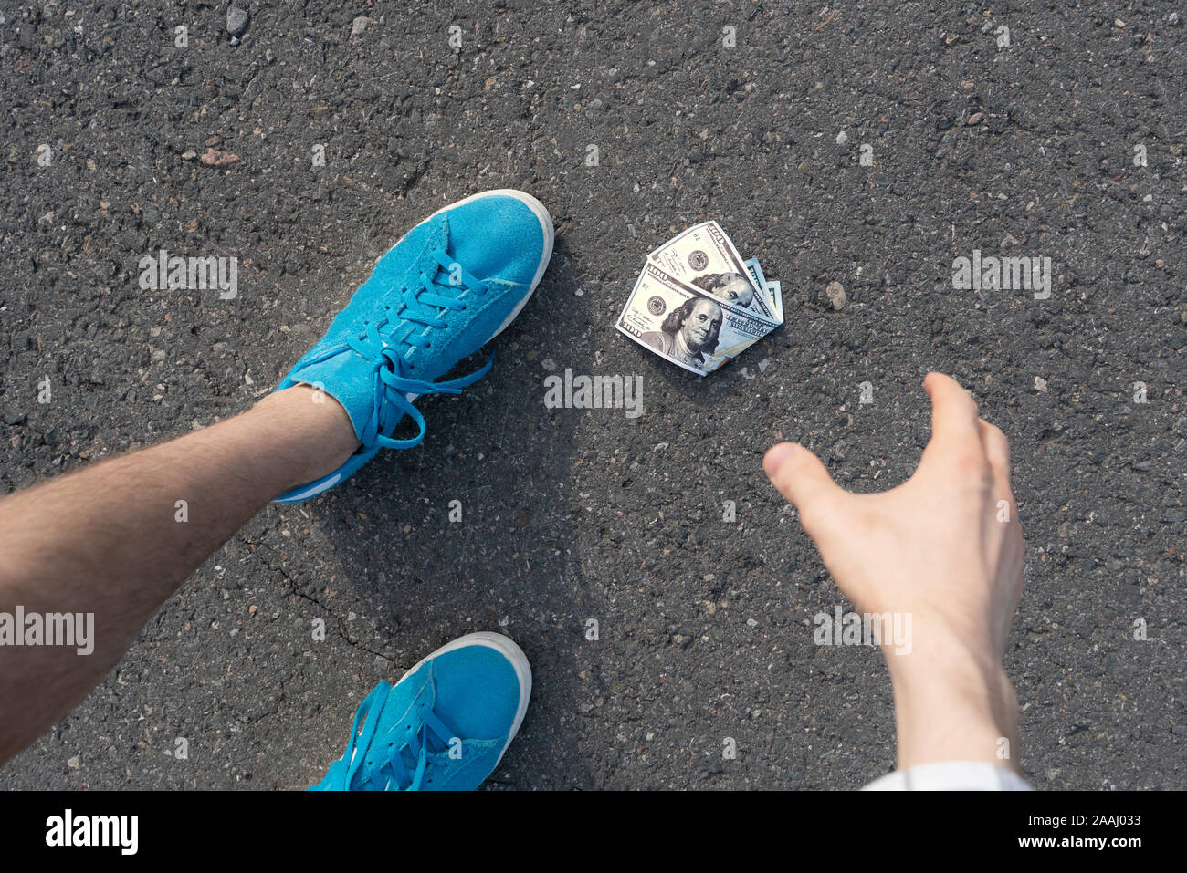 Persona trova la carta moneta perduta e lasciato cadere sul terreno asfaltato all'aperto Foto Stock