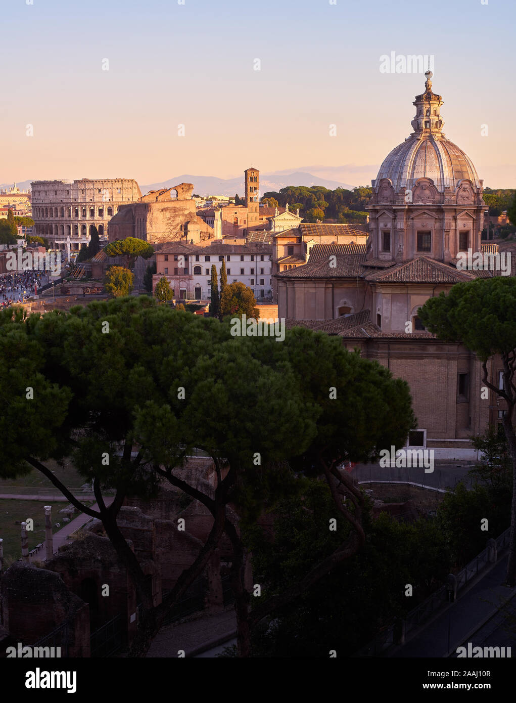 Vista panoramica della città di Roma al tramonto, con cupole di chiese e il Colosseo Foto Stock