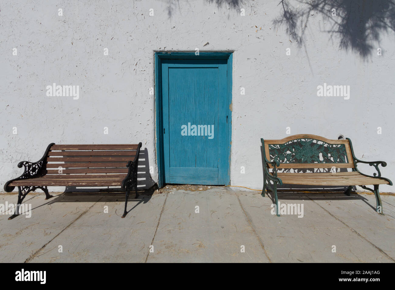 Un muro bianco con un unico sportello blu e due panche. Foto Stock