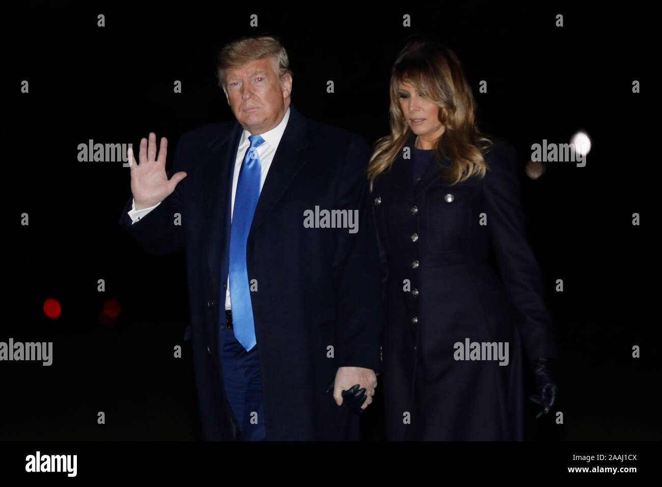 Il Presidente degli Stati Uniti, Trump onde come egli cammina con la prima signora Melania Trump sulla South Lawn della casa bianca dopo il loro ritorno a Washington DC da Dover, Delaware dove hanno testimoniato la dignitosa di trasferimento i resti di due soldati americani uccisi in Afghanistan il 21 novembre 2019. Credito: Yuri Gripas/Piscina via CNP /MediaPunch Foto Stock