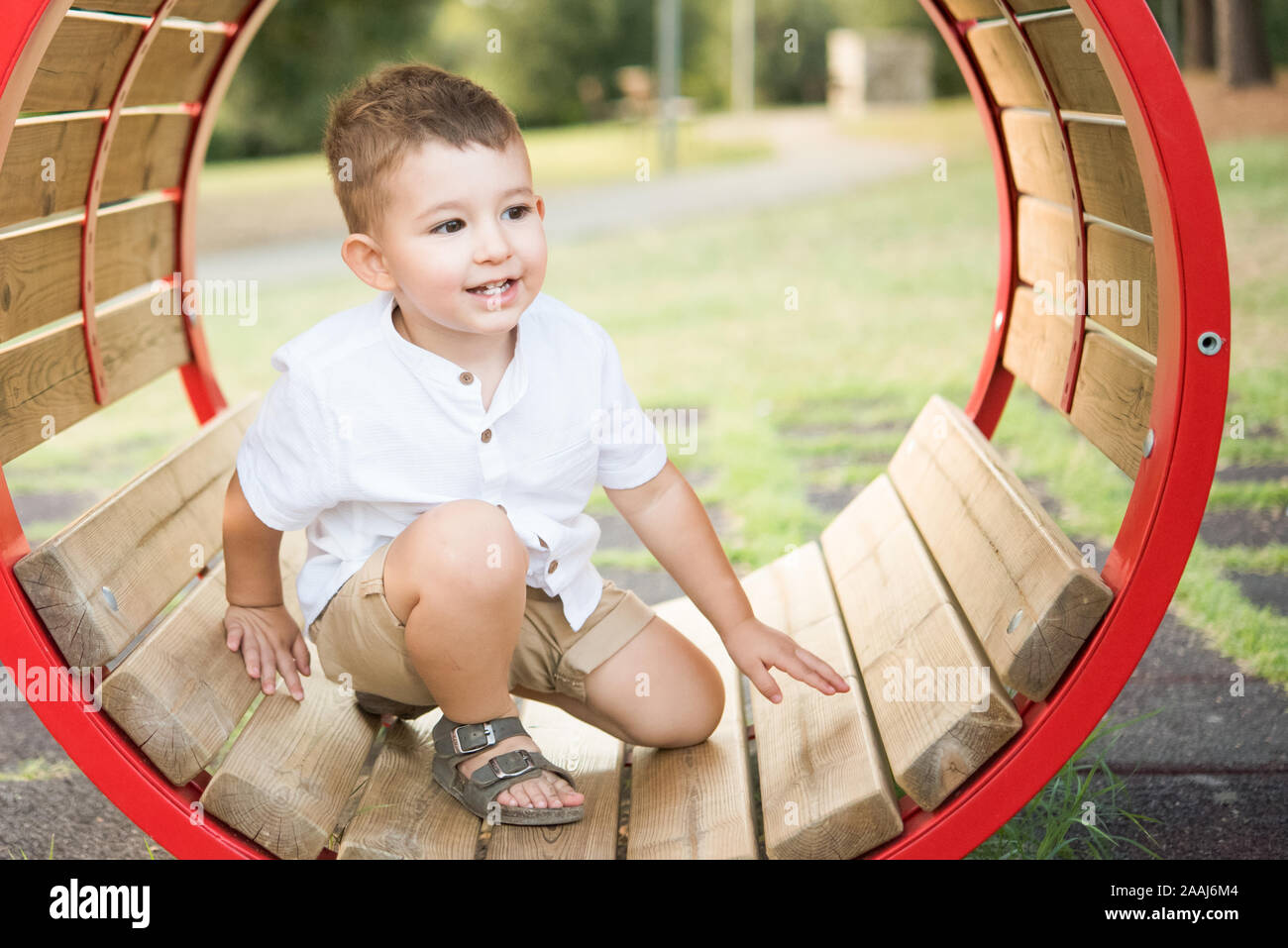 Il Toddler inginocchiarsi all'interno di oscillazione circolare in posizione di parcheggio Foto Stock