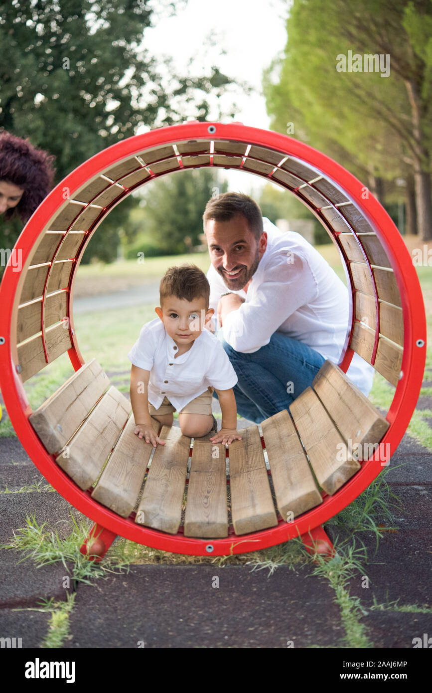 Padre figlio a guardare la riproduzione in oscillazione circolare in posizione di parcheggio Foto Stock
