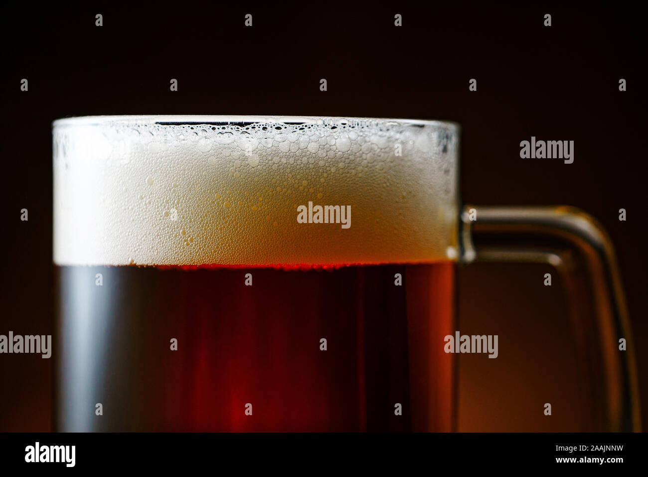 Dark boccale di birra con schiuma bianca su sfondo scuro vicino fino Foto Stock