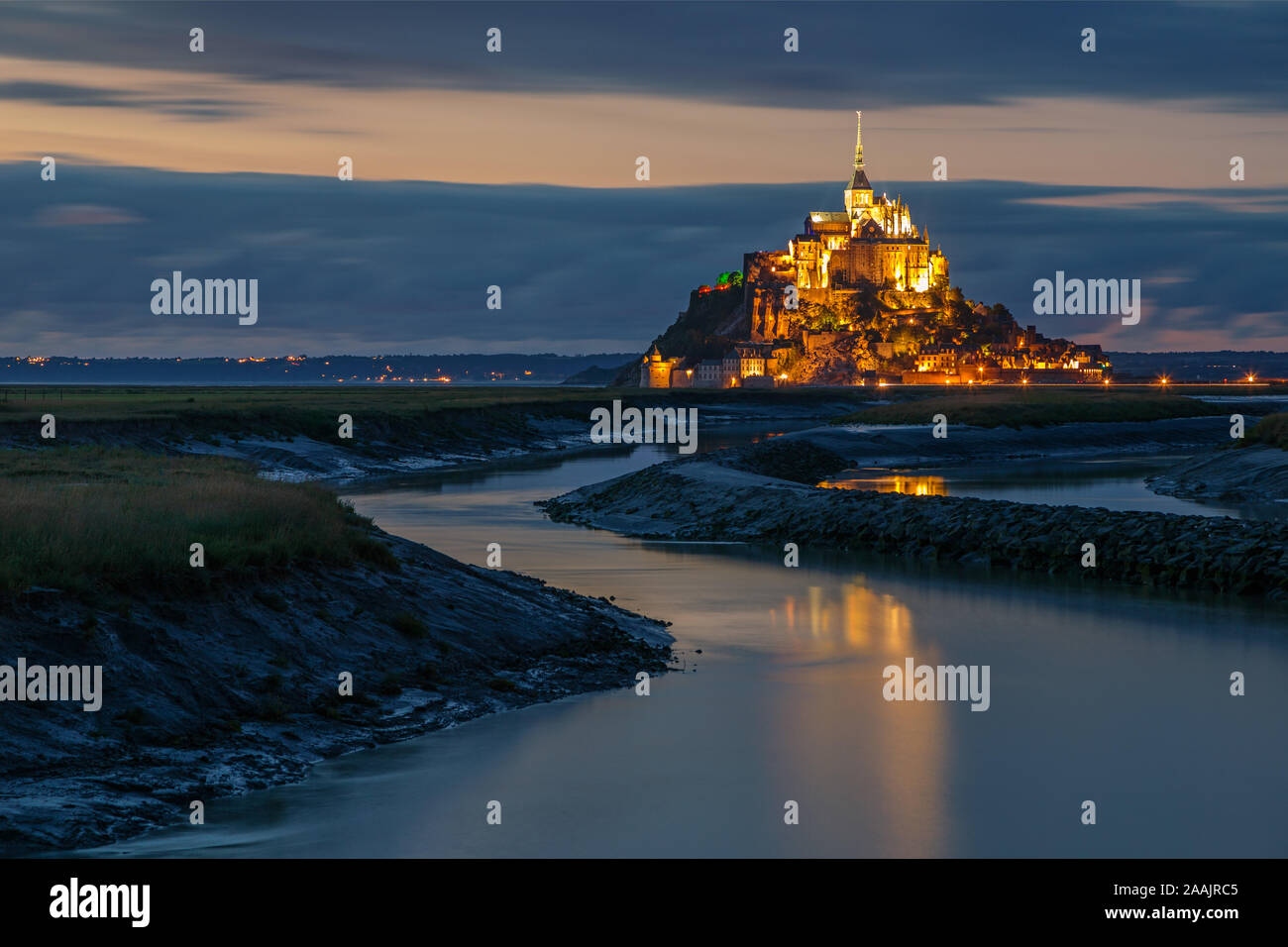 La Normandia, Francia. Gli illuminati Mont Saint Michel si riflette sull'acqua Foto Stock