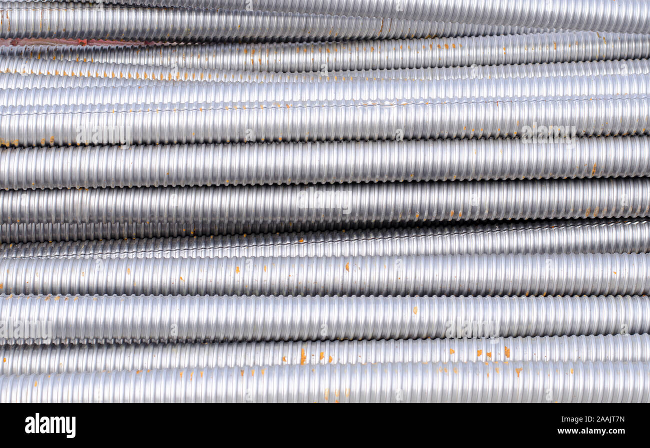 Tubi metallici in una pila su un sito in costruzione Foto Stock