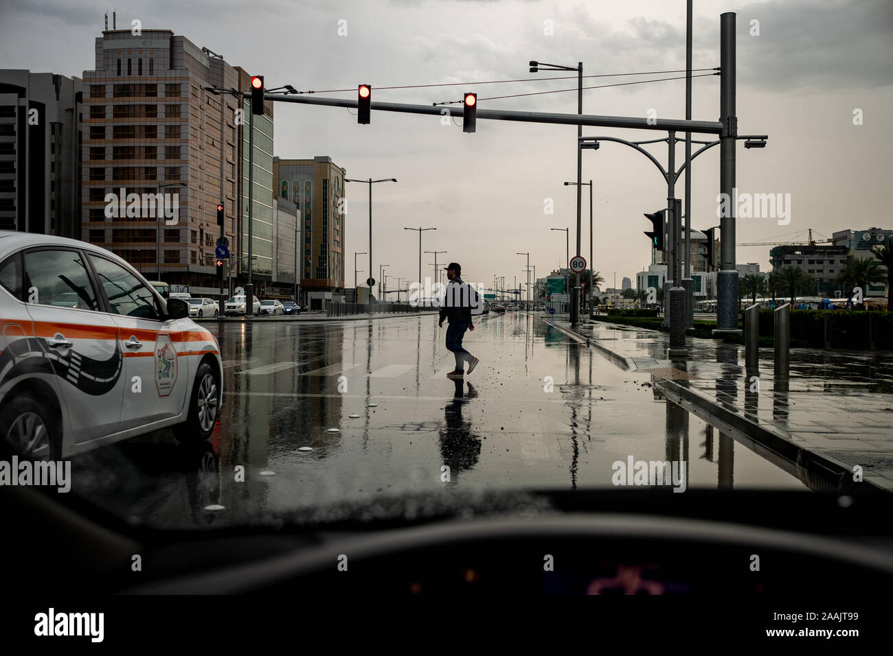 Una persona che attraversa la strada mentre piove di Abu Dhabi, Emirati arabi uniti Foto Stock