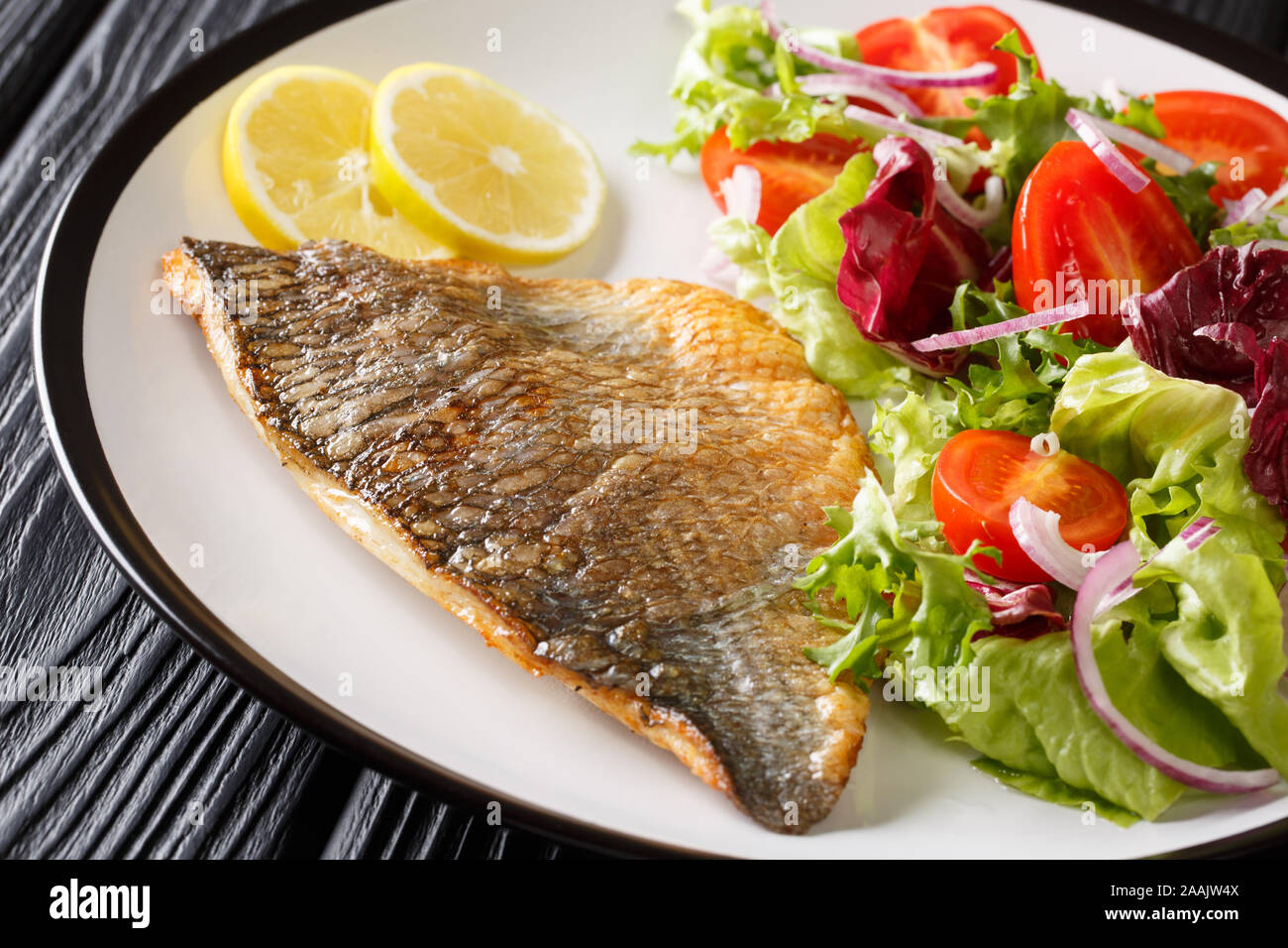 Fried orata filetto di pesce con un contorno di insalata di verdure close-up su una piastra sul tavolo orizzontale. Foto Stock