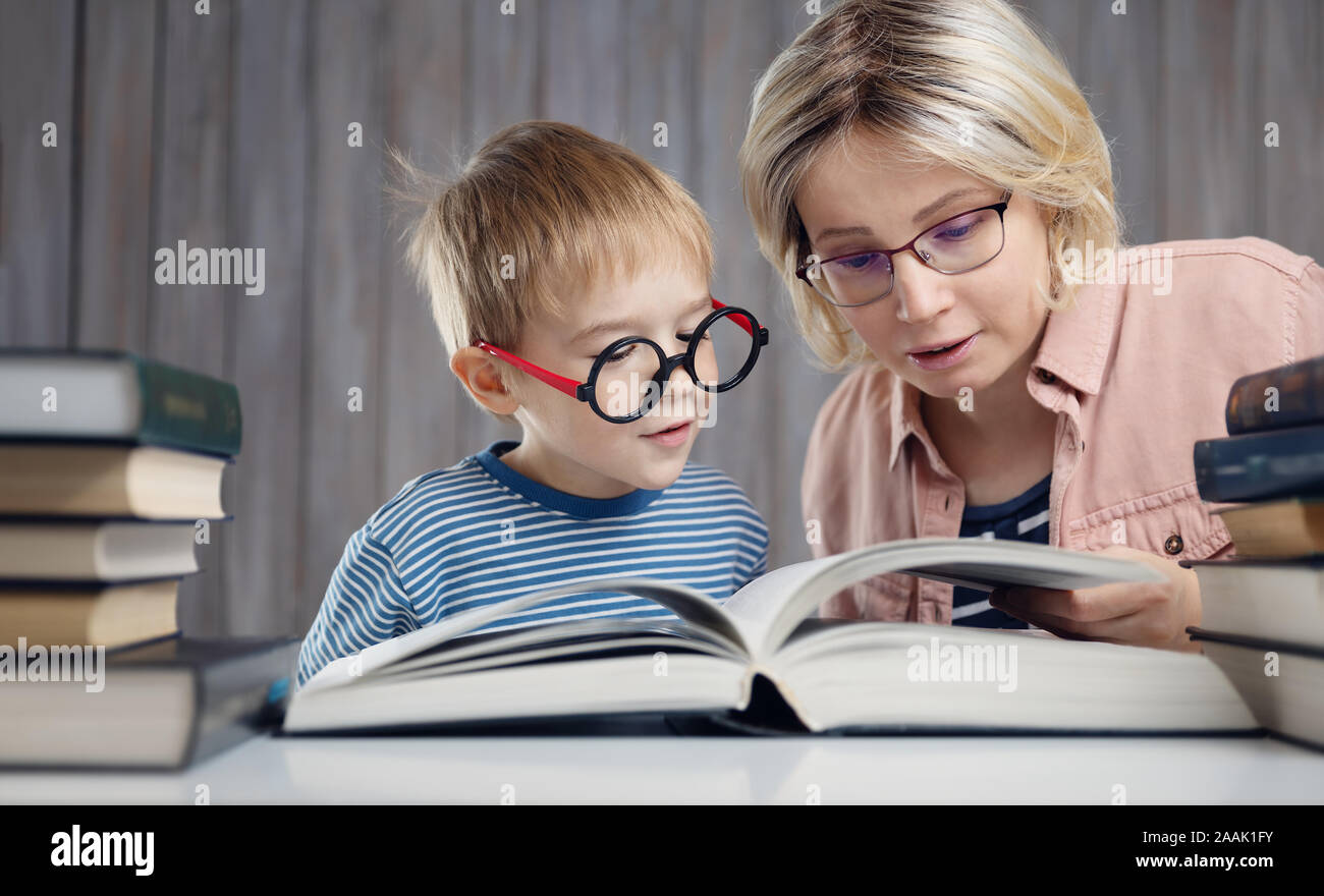 Cinque anni bambino la lettura di un libro a casa con la madre Foto Stock