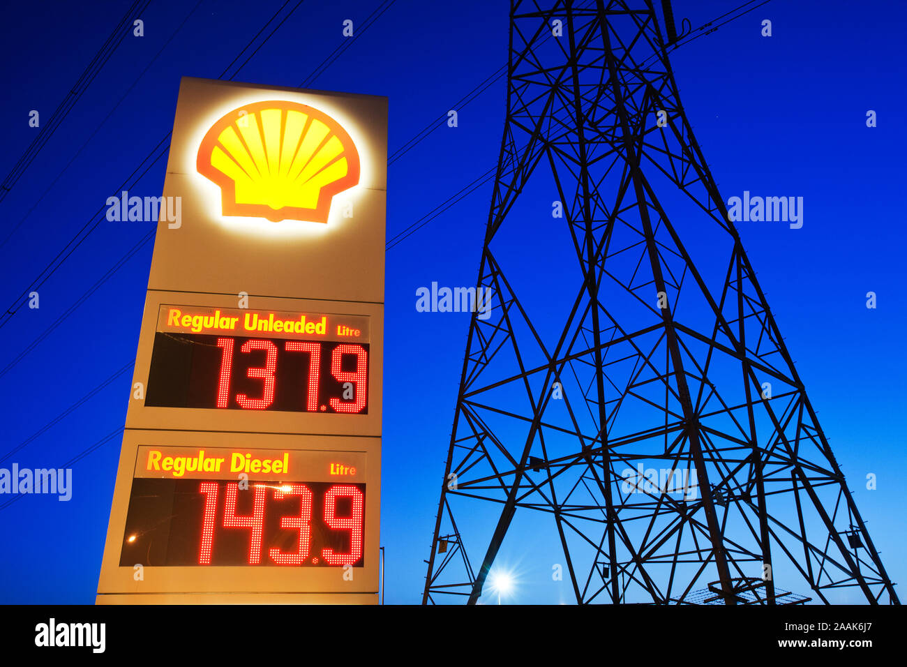 Caro prezzi benzina in Billingham su Teeside, Regno Unito, con un traliccio di elettricità. Questa cruda immagine presa al tramonto sembra riassumere la nostra dipendenza da energ Foto Stock