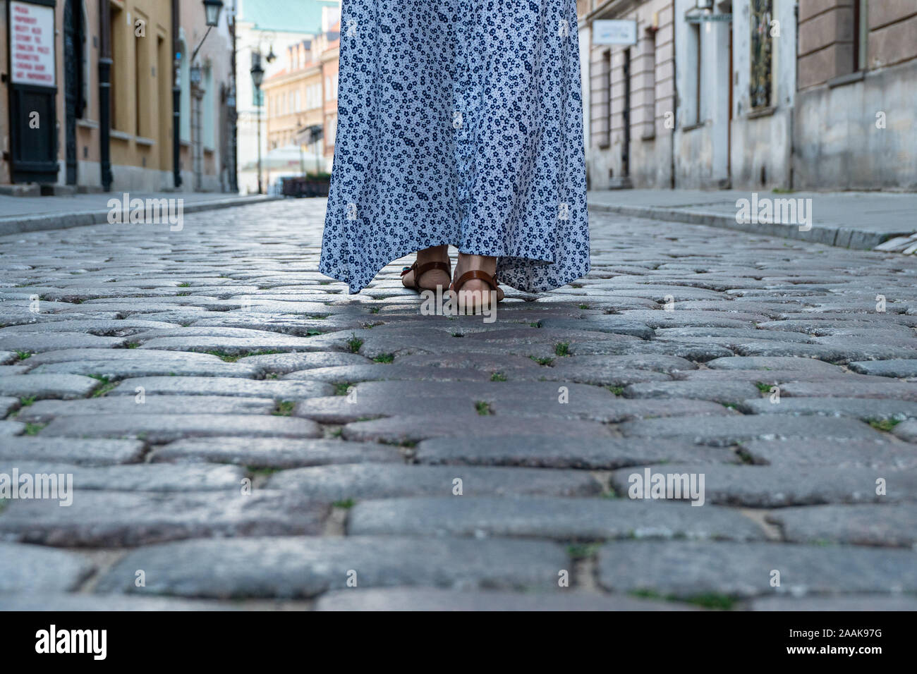Gambe femmina in sandali a piedi sull'acciottolato su una strada di città Foto Stock