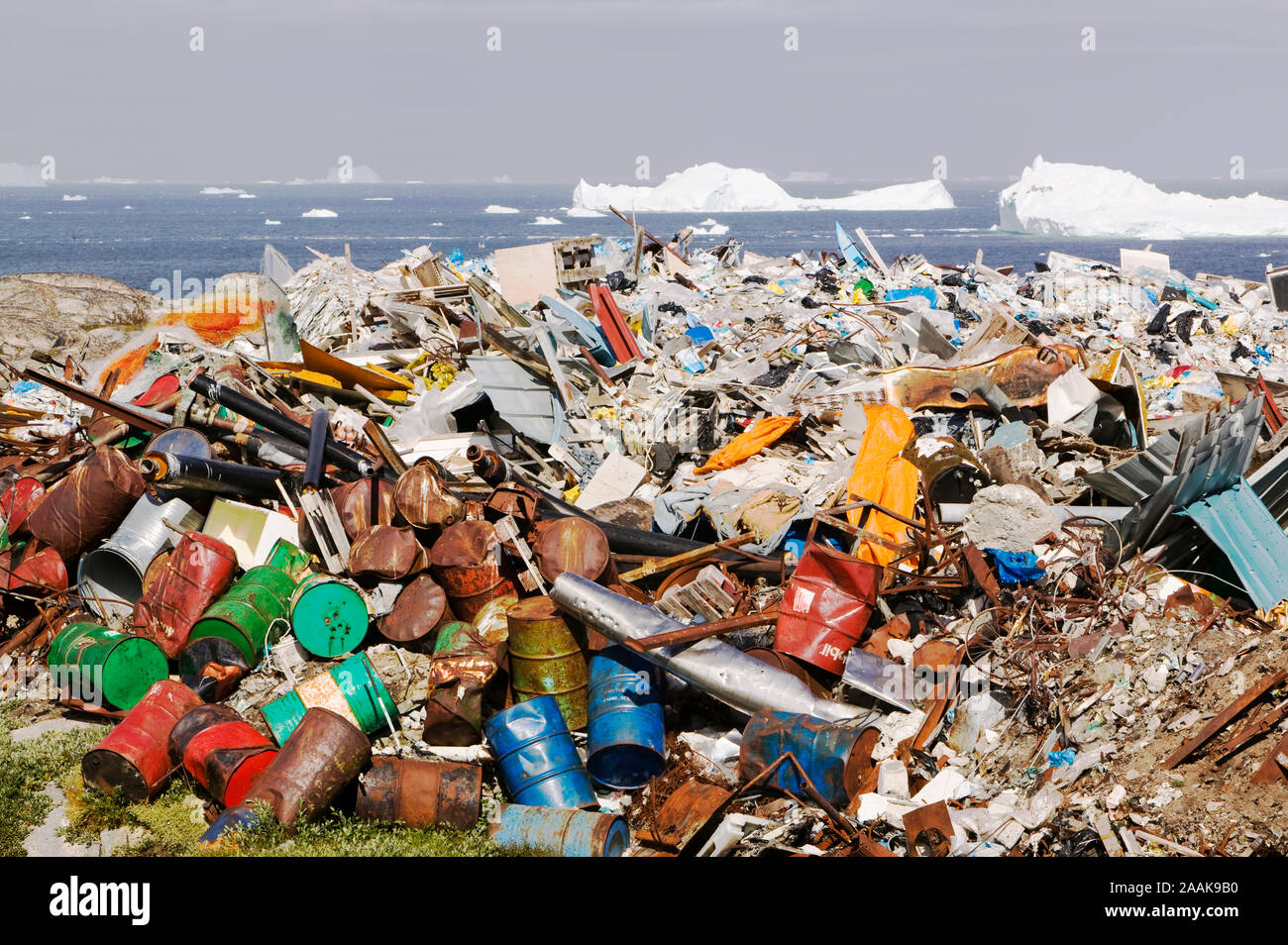 Olio e ghiaccio. Barili di olio oggetto di dumping nella tundra al di fuori di Illulissat in Groenlandia con gli iceberg dietro dal Illulissat fiordo di ghiaccio. Il ghiaccio Illulissat f Foto Stock