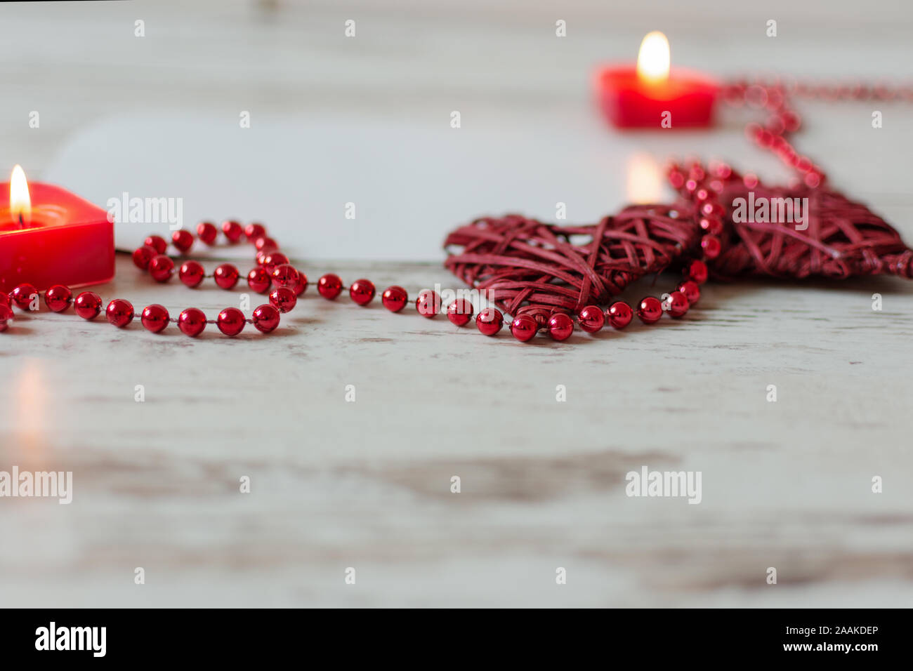 Cuori con cordone rosso catena e candele su sfondo di legno. San Valentino o scheda di nozze concetto con copia spazio . Foto Stock