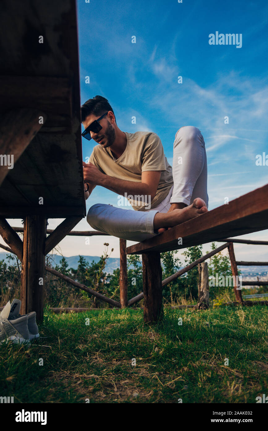 Uomo bello holding smartphone durante l udienza in natura contro il cielo blu Foto Stock