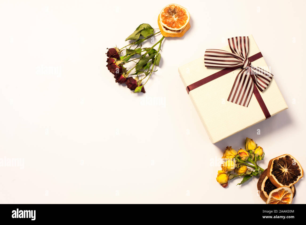 Confezione regalo di rosso e giallo le rose su uno sfondo bianco. Arancio secco come decorazione. Foto Stock