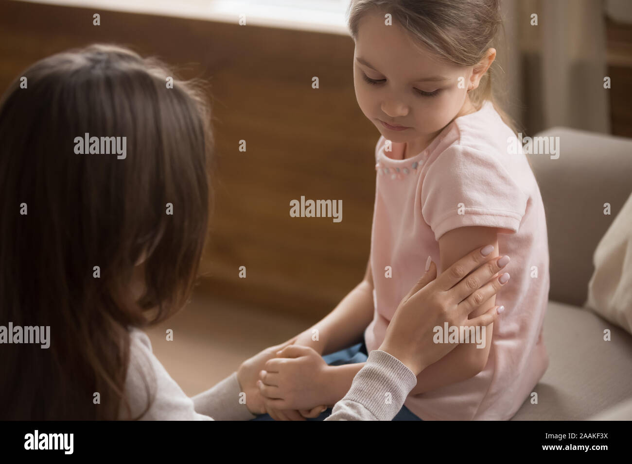 Mom toccare accarezzare infelice figlia preschooler seduta sul lettino Foto Stock