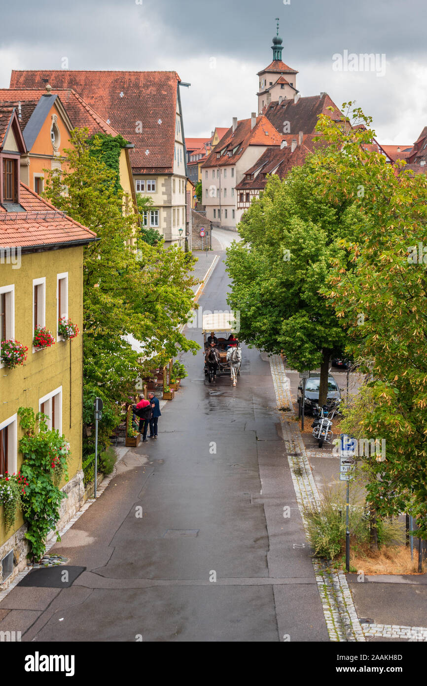 Durante una giornata estiva di pioggia а carrozza trainata da cavalli che porta turisti intorno alla città medievale di Rothenburg ob der Tauber, Franconia, Baviera. Foto Stock