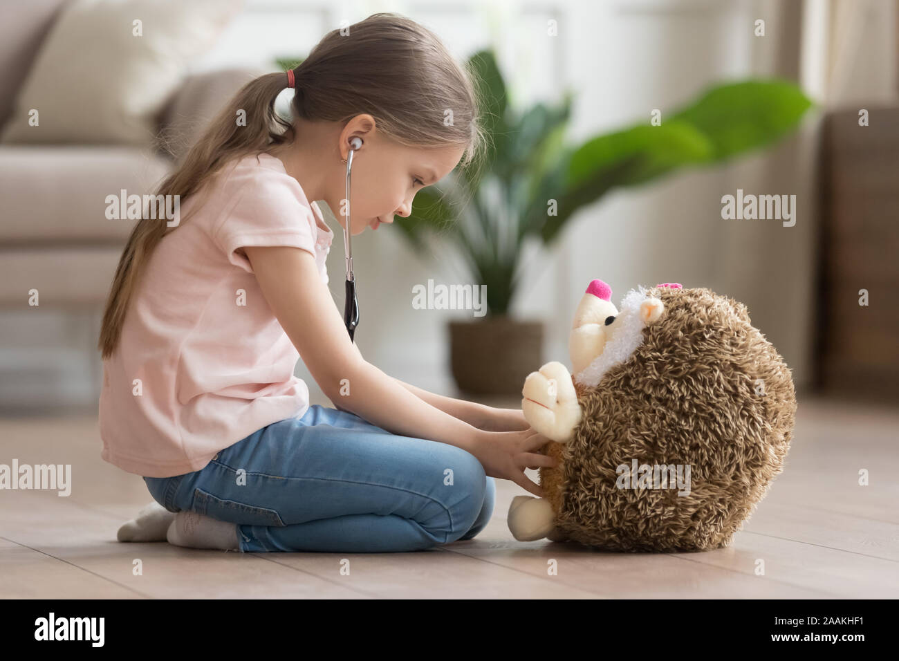 Carino bambina gioca medico gioco con hedgehog giocattolo Foto Stock