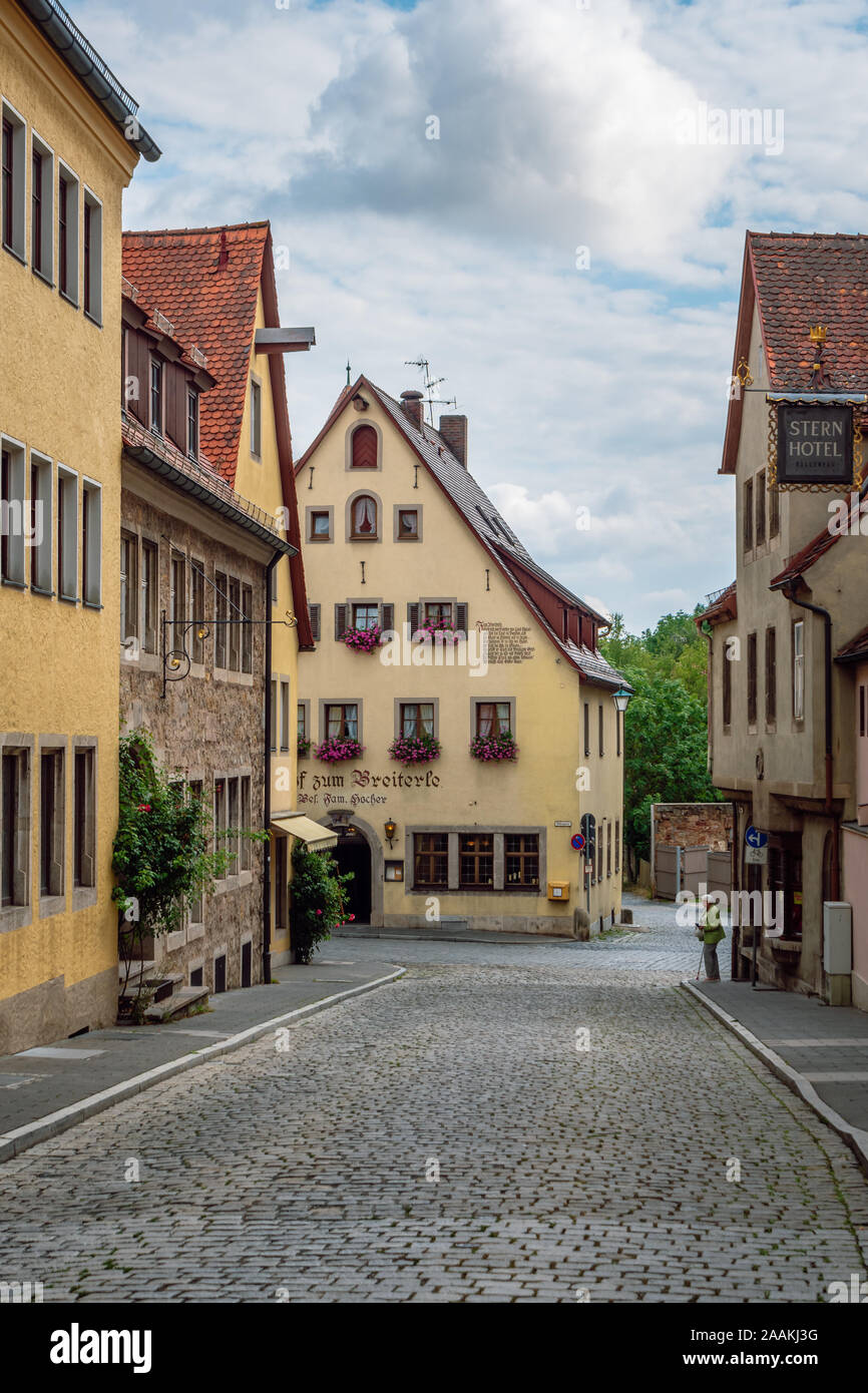 Vista della strada asfaltata al fondo della quale è una casa tradizionale con un hotel. La cittadina medievale è parte della famosa strada romantica in Germania. Foto Stock