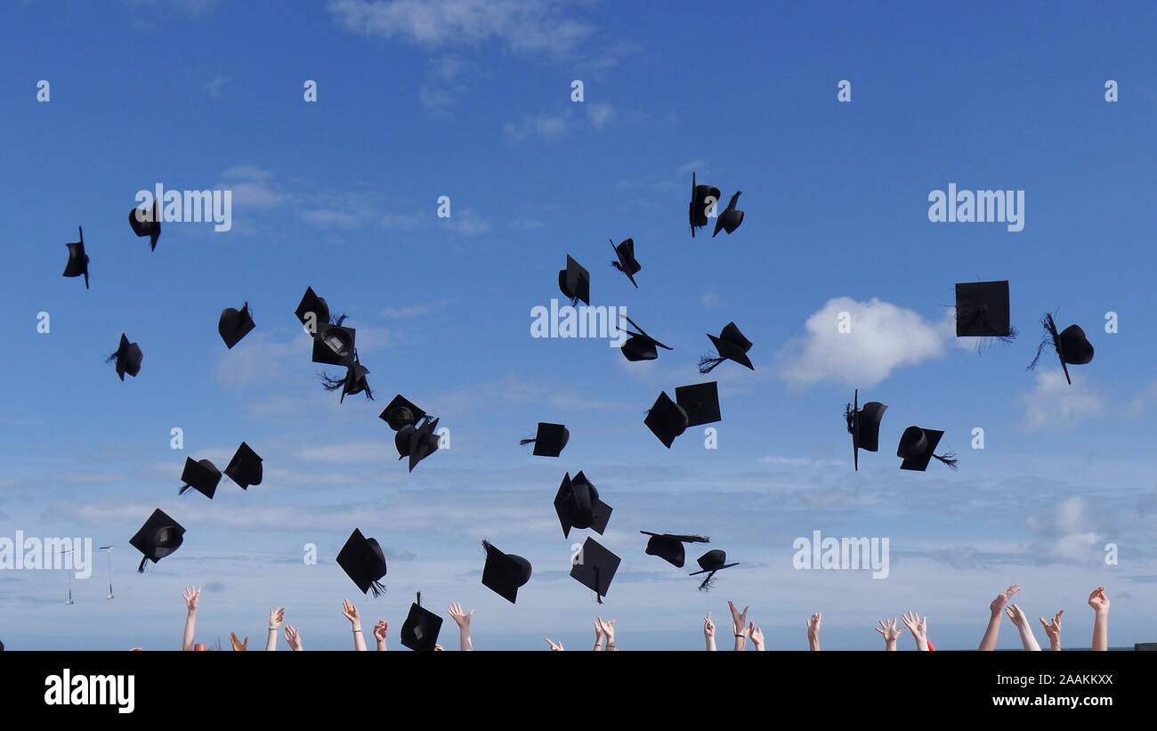 I laureati celrebating il loro successo da buttare i tappi e schede di mortaio in aria Foto Stock