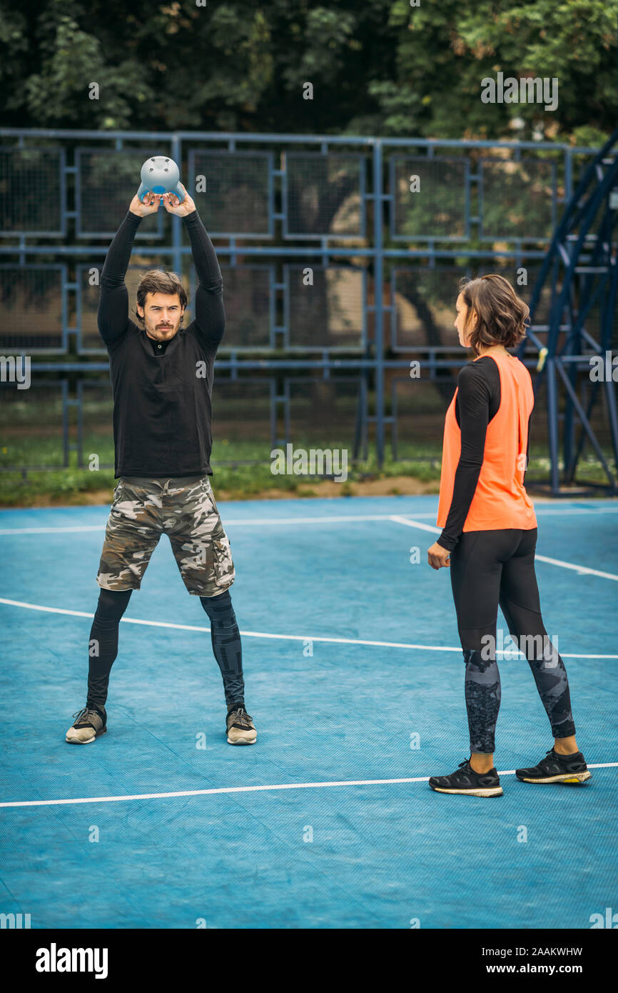 Montare e sano personal trainer che mostra kettlebell esercizio ad una femmina di client. Foto Stock