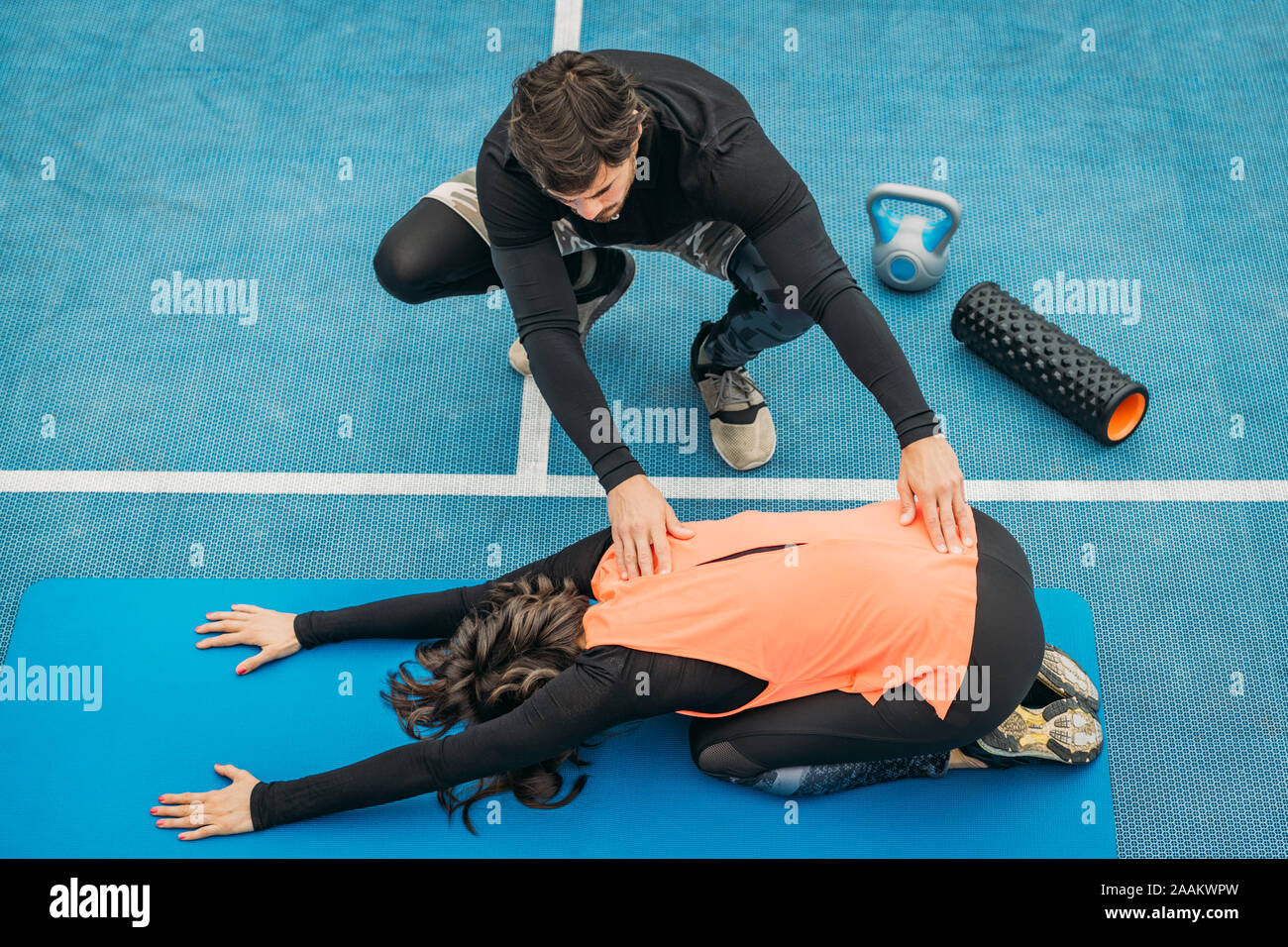 Montare la giovane donna facendo esercizi di stretching dopo un allenamento con personal trainer. Foto Stock