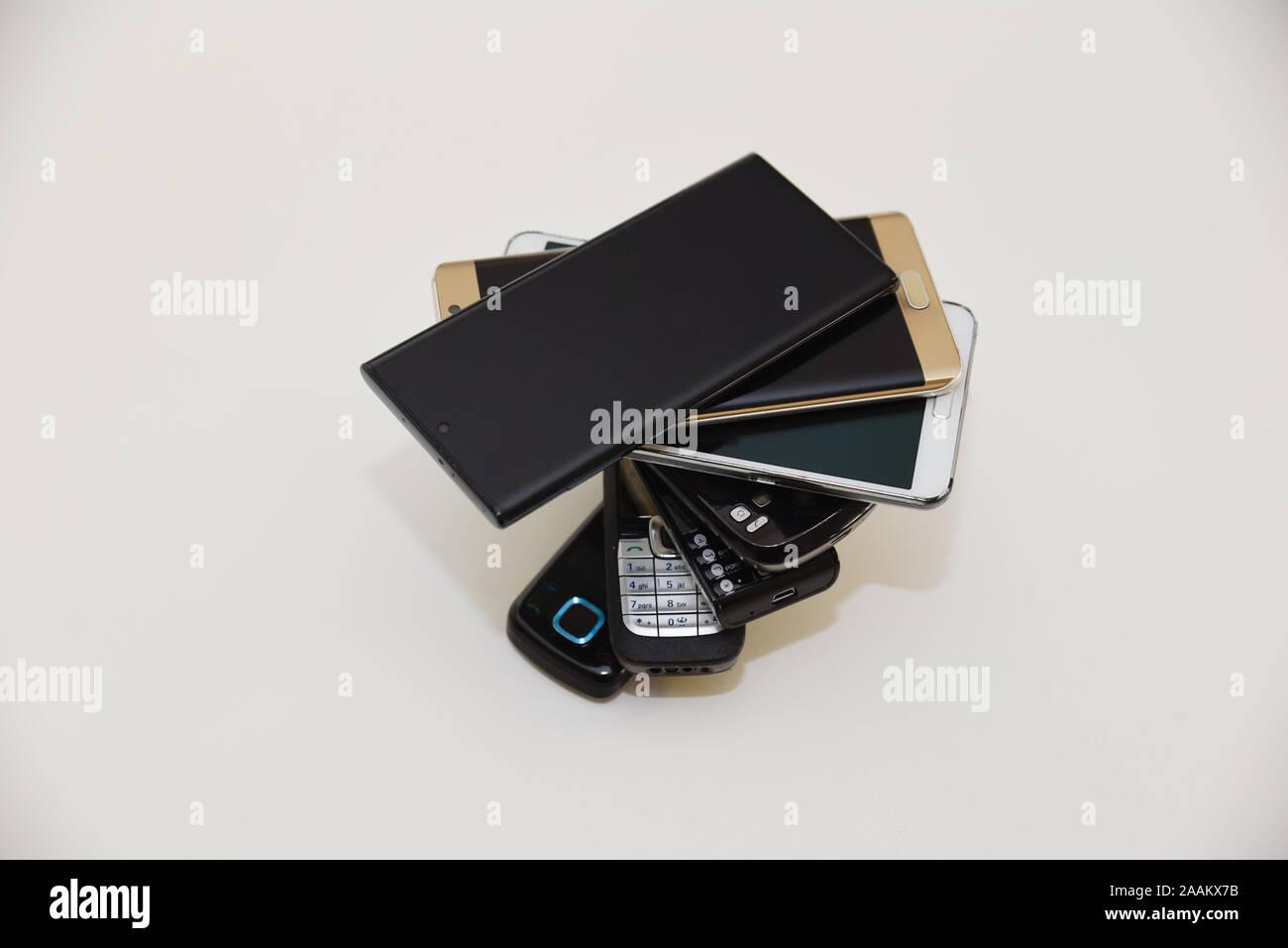 Telefoni impilati gli uni sugli altri in una forma a spirale che mostra l'evoluzione di ritorno dal GSM e 3G i modelli fino a 5G tecnologia utilizzata su smartphone più recenti Foto Stock