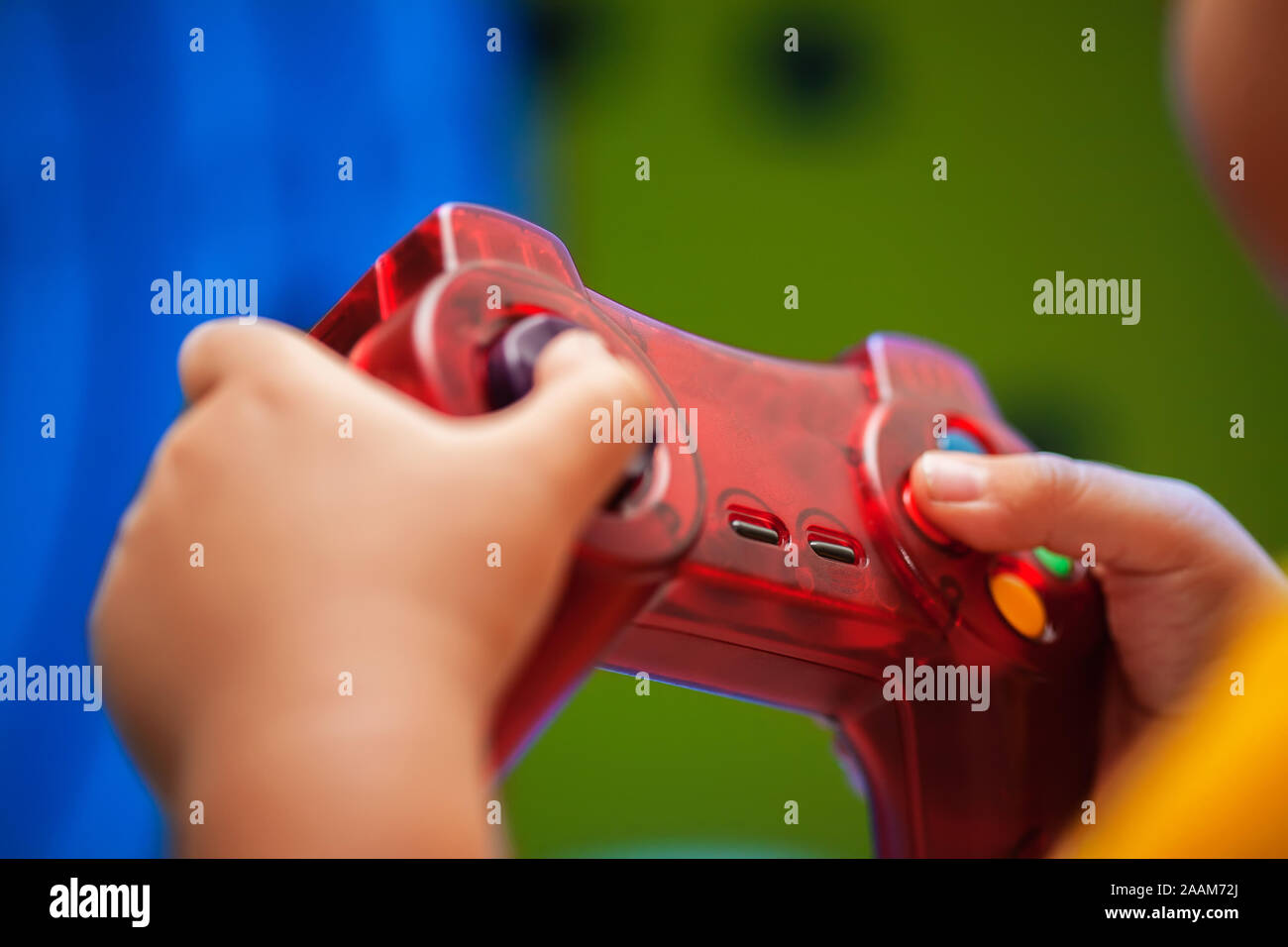 Close-up di un bambino la mano che regge un video controller di gioco durante la riproduzione di un gioco colorato sullo schermo. Foto Stock
