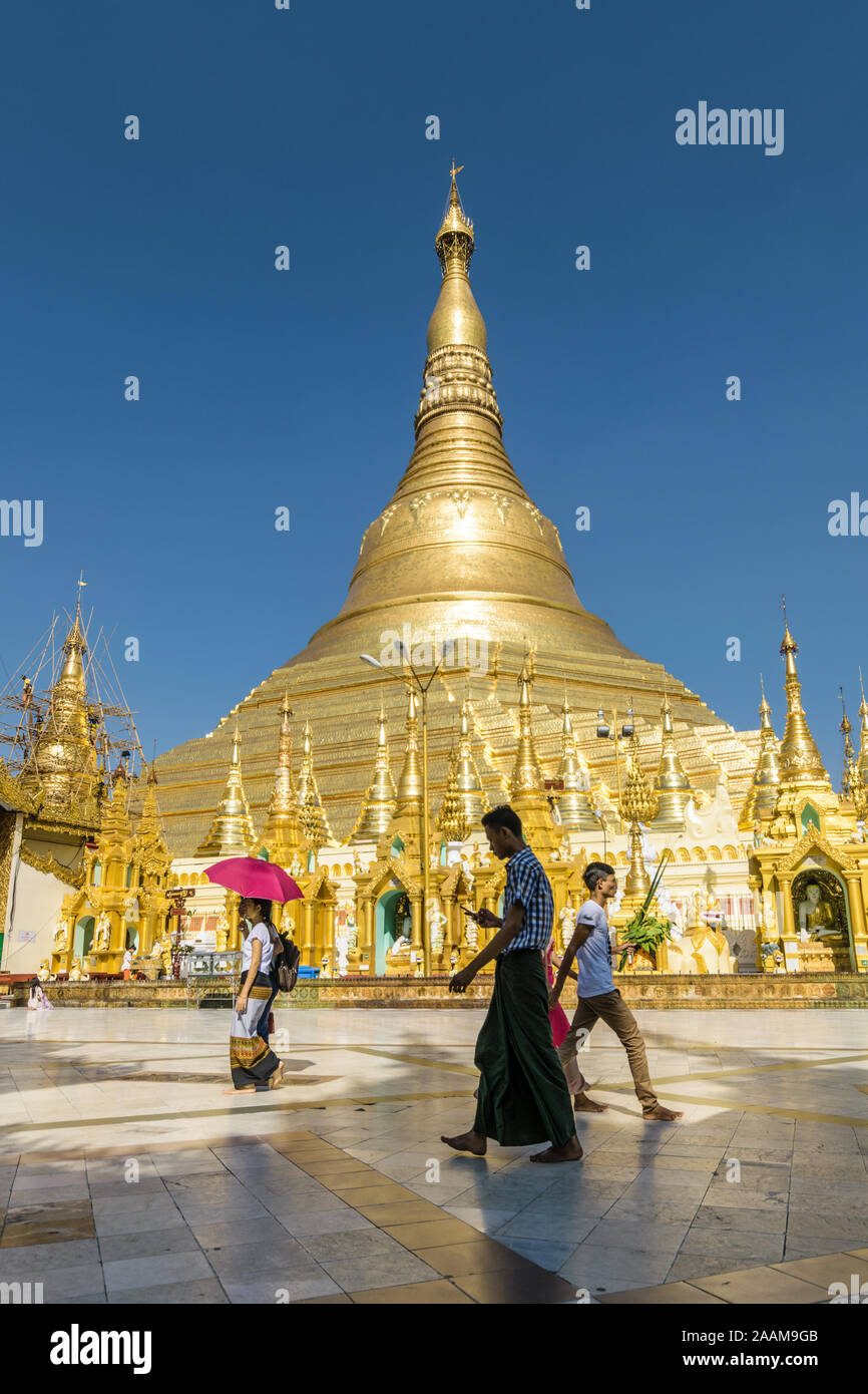 La gente del posto che va circa la loro vita alla Shwedagon pagoda sito. Questo tempio buddista è la più importante del paese. Foto Stock