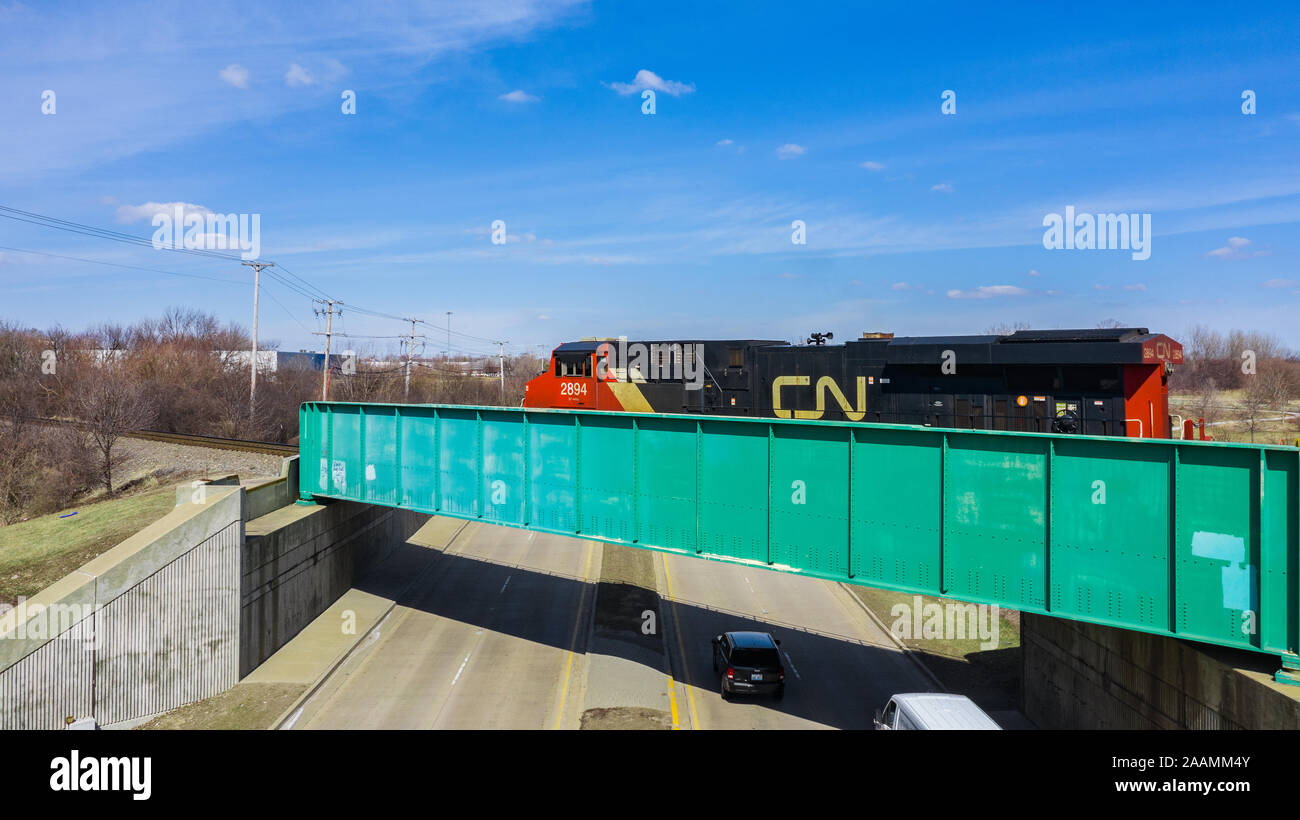 Un drone / vista aerea di un treno trasporta i contenitori di spedizione andando su una strada. Foto Stock