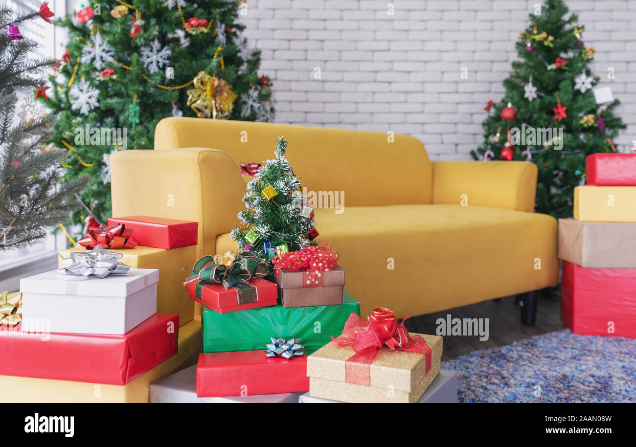 Natale soggiorno, divano giallo con alberi di Natale, confezioni regalo e le decorazioni di Natale Foto Stock