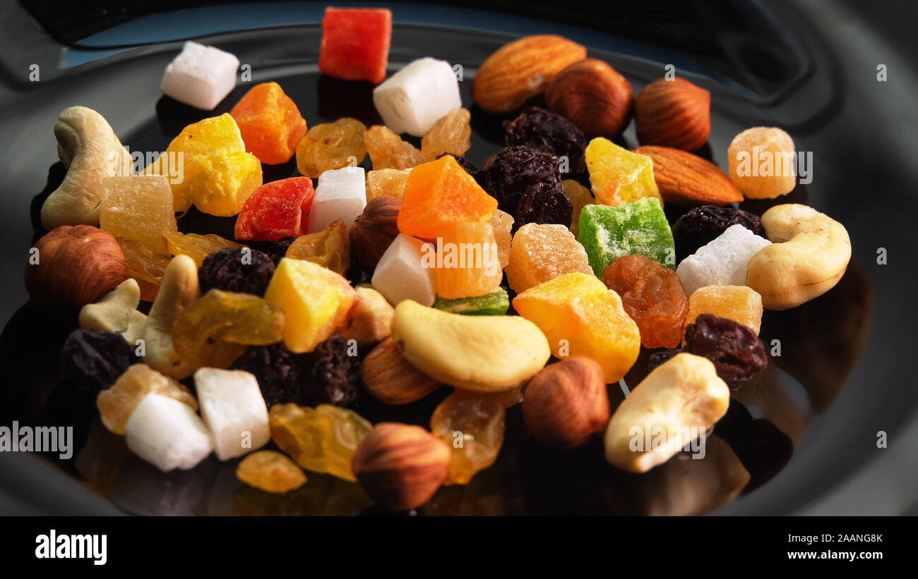 Tutti frutti. Mix di frutta secca (uva passa, cedro, mango) e dadi (mandorle, nocciole) su un nero laccato piatto Foto Stock