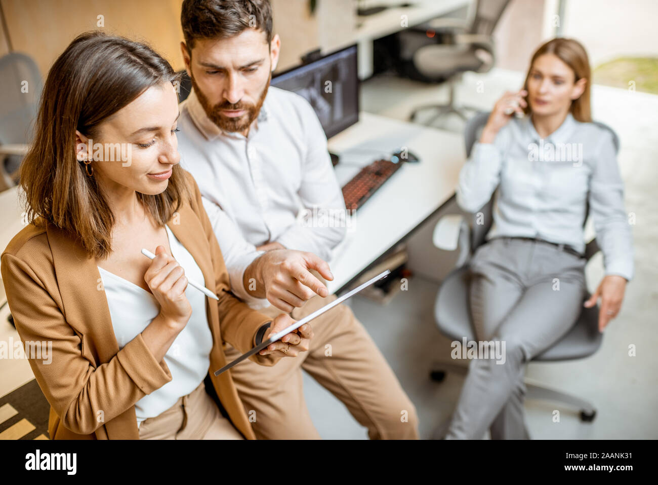 I colleghi aventi qualche lavoro creativo utilizzando tavoletta digitale e matita in ufficio moderno studio. Concetto di progettazione digitale su un tablet Foto Stock