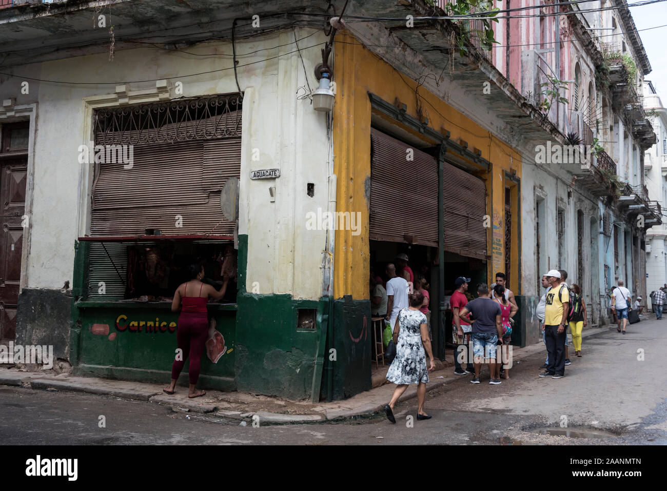 Un residente alla vetrina della macelleria con una piccola coda ad un frutteto dietro l'angolo nella città Vecchia dell'Avana a Cuba. Foto Stock