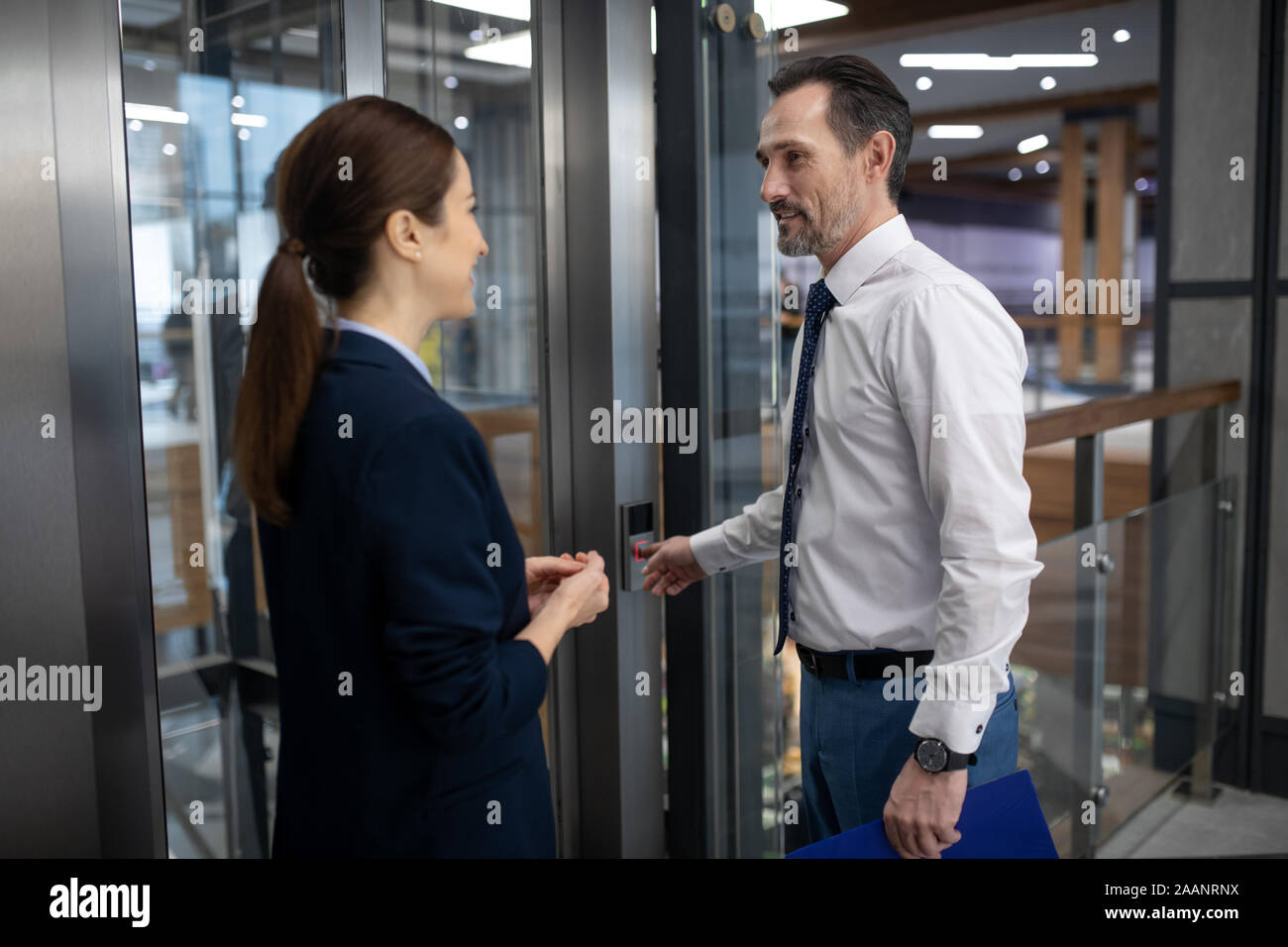 Paio di imprenditori tramite ascensore mentre la voce per la riunione Foto Stock