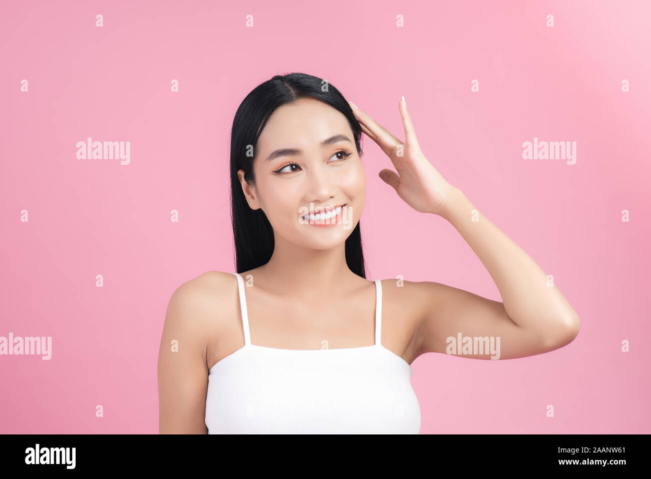 Giovane bella donna asiatica avendo cura dei suoi capelli. Ritratto di bellezza naturale , per il make-up, bellezza viso, isolate su sfondo rosa. Foto Stock