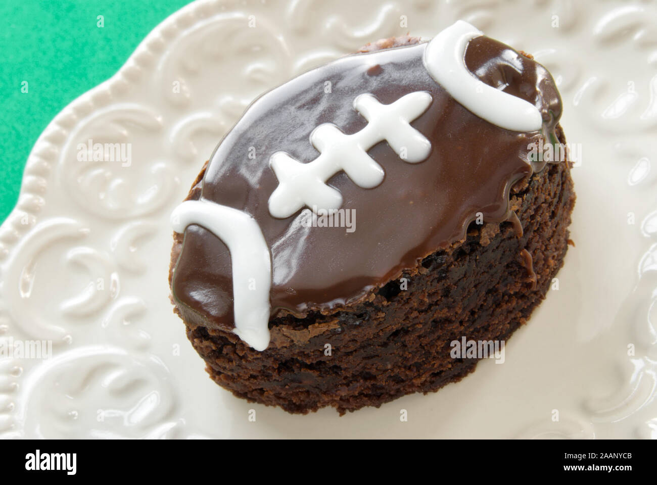 In casa a forma di pallone da football double fudge ghiacciata di cioccolato brownie con piping bianco servito su una piastra. Foto Stock