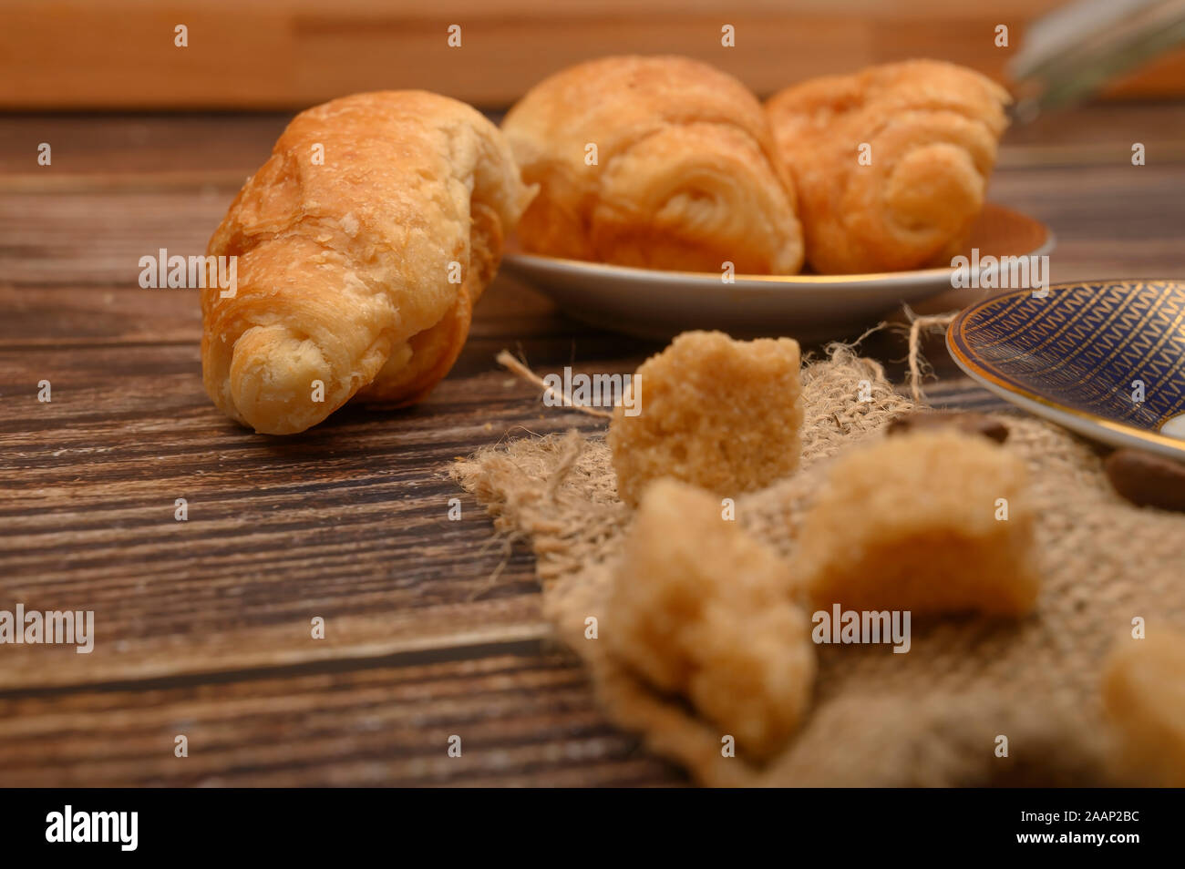 Lo zucchero di canna fette e croissant su uno sfondo di legno. Close up Foto Stock