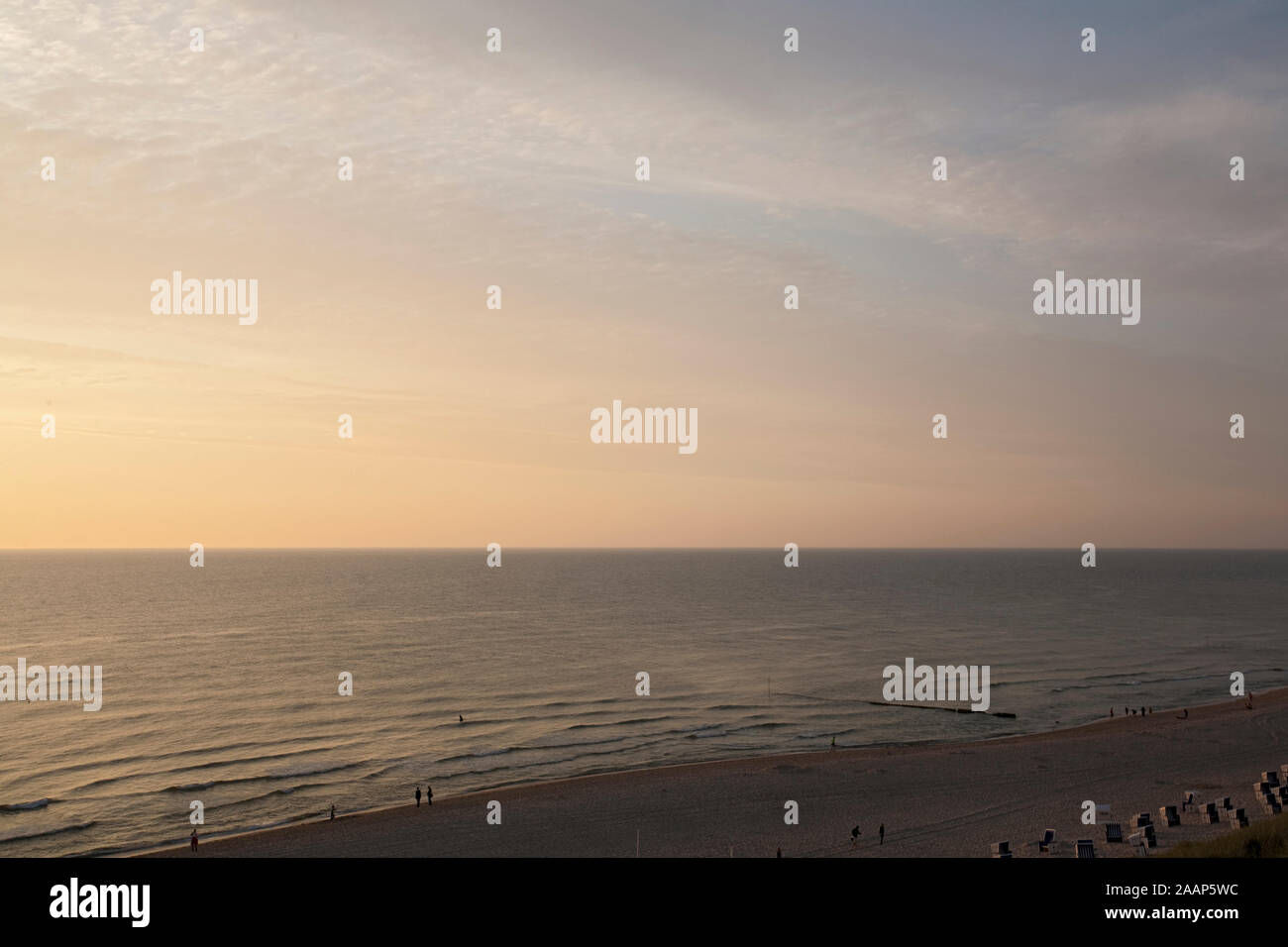 Untergehende Sonne zwischen Meer und Wolken am Strand bei Wenningstedt auf Sylt Foto Stock